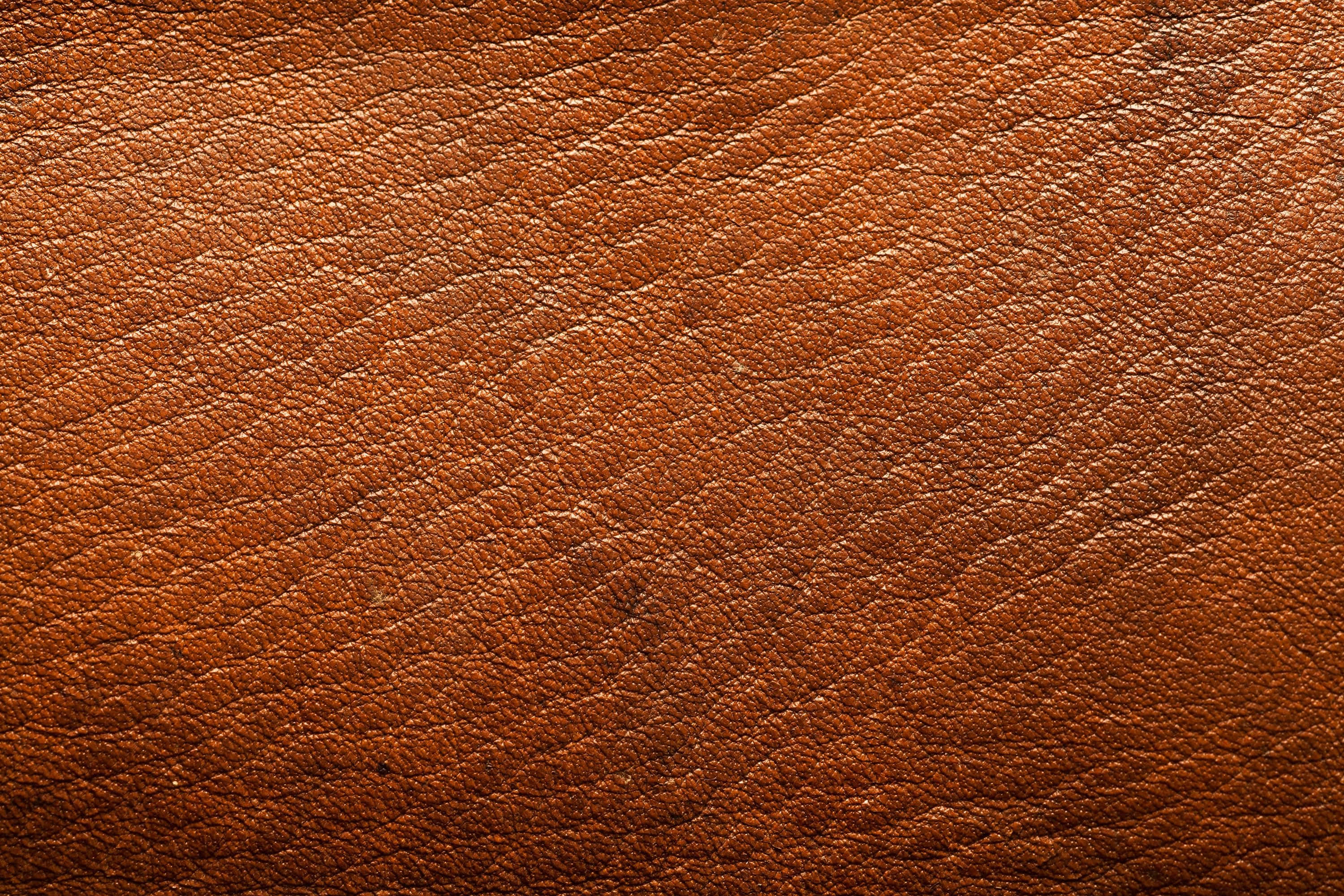 Leather 桌布 壁紙 — 柔和燈光下，天然紋理及細微質感變化的濃郁棕色皮革特寫。