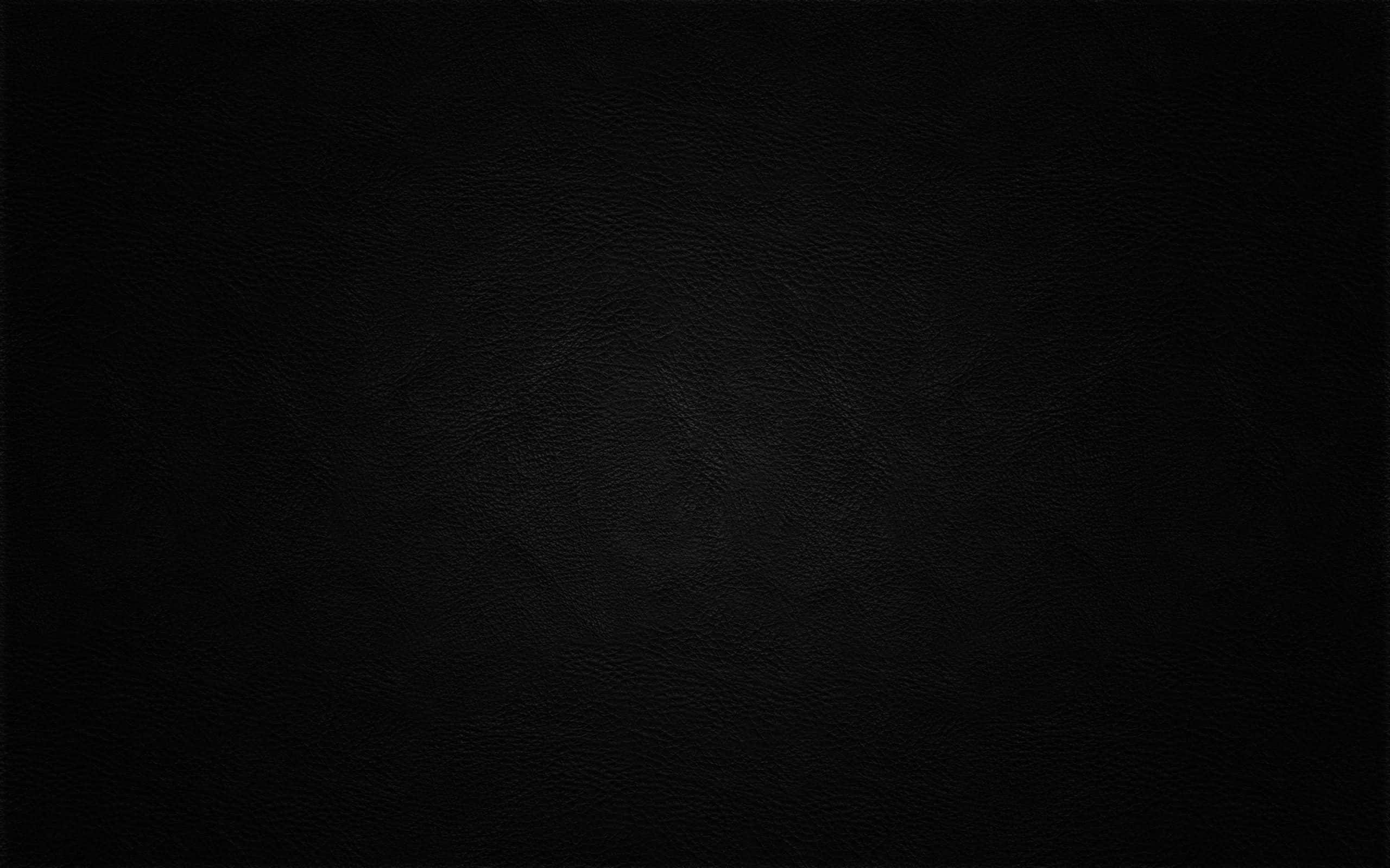 dark black 桌布 壁紙 — 柔和燈光下光滑黑色皮革表面的特寫，帶有細微的粒面紋理。