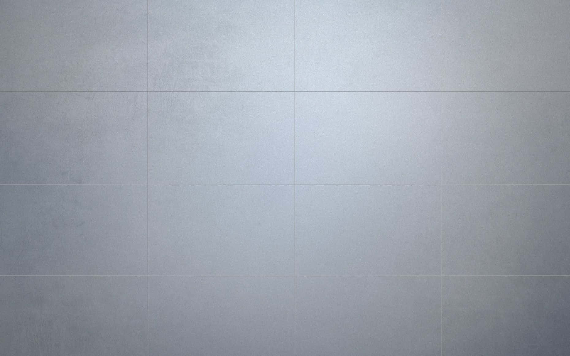 Tile 桌布 壁紙 — 柔和燈光下淺灰色瓷磚牆的特寫，帶有細微紋理和模糊的填縫線。