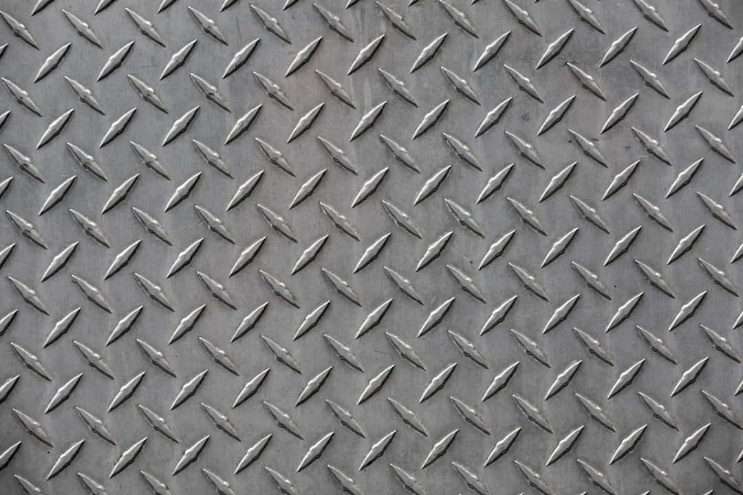 Diamond Plate 桌布 壁紙 — 柔和燈光下金屬表面重複凸起菱形圖案的近距離特寫。