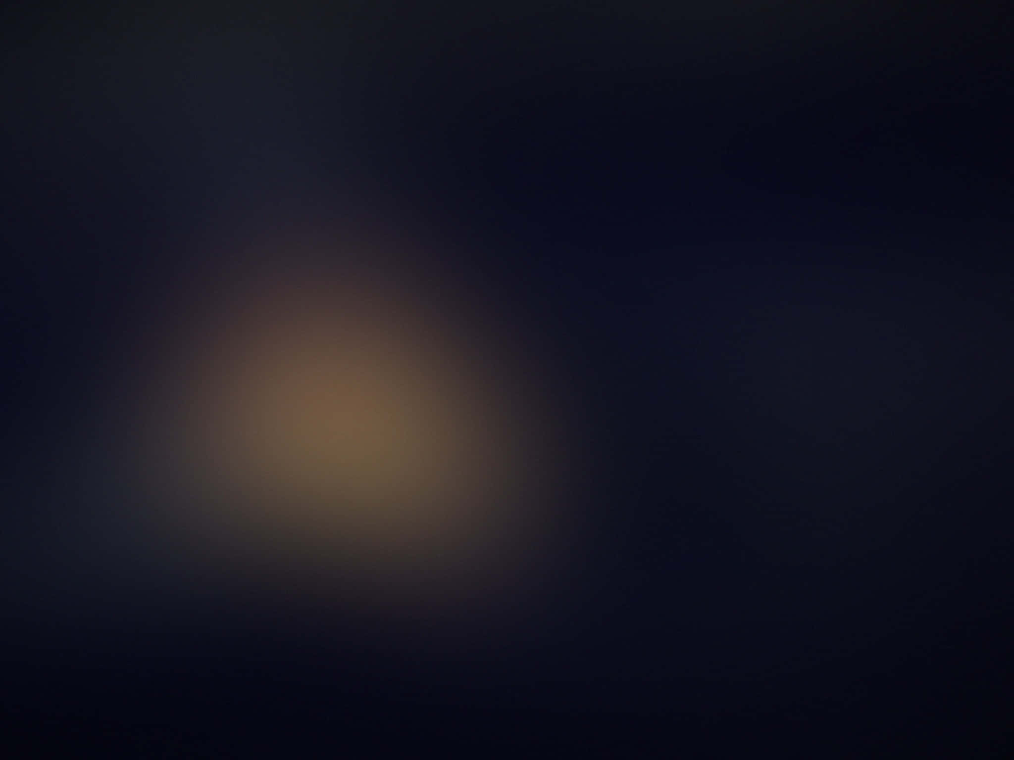 Black Blur 桌布 壁紙 — 柔和發光的琥珀色光線逐漸消失在深靛藍的黑暗中，營造出寧靜而神秘的氛圍。