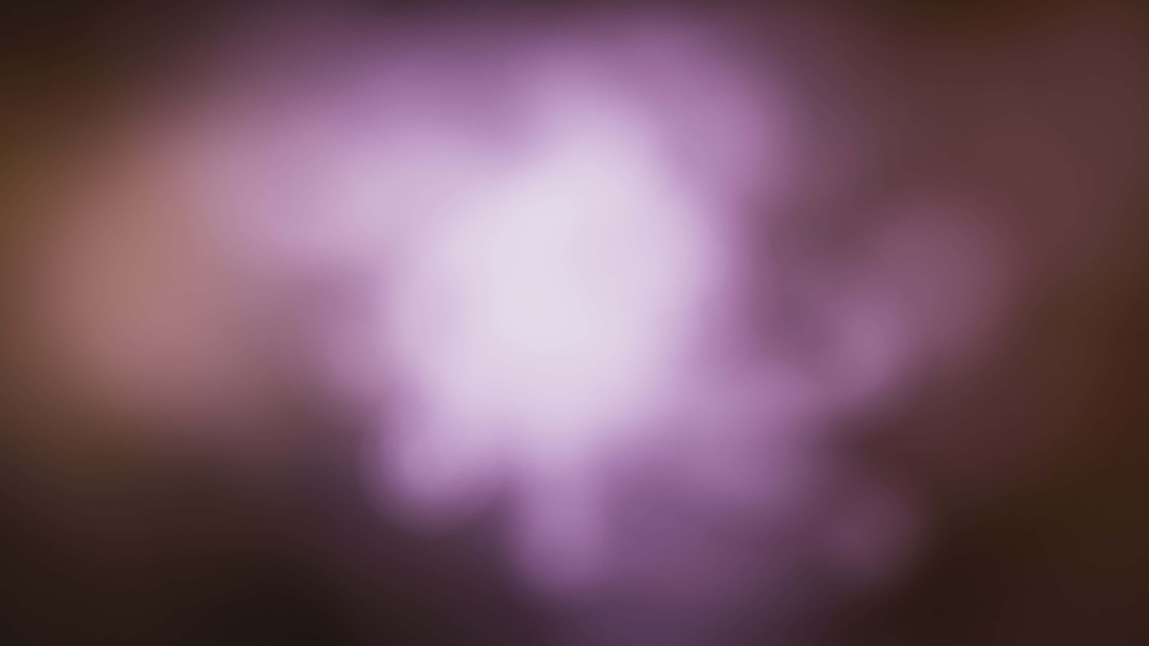 Blurry 桌布 壁紙 — 柔和發光的紫色光線從中心散發，映襯著黑暗模糊的背景。