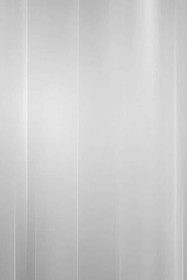 Light Gray iPhone 桌布 壁紙 — 柔和的垂直光線穿過薄紗白色窗簾，在極簡主義的室內空間中閃耀。