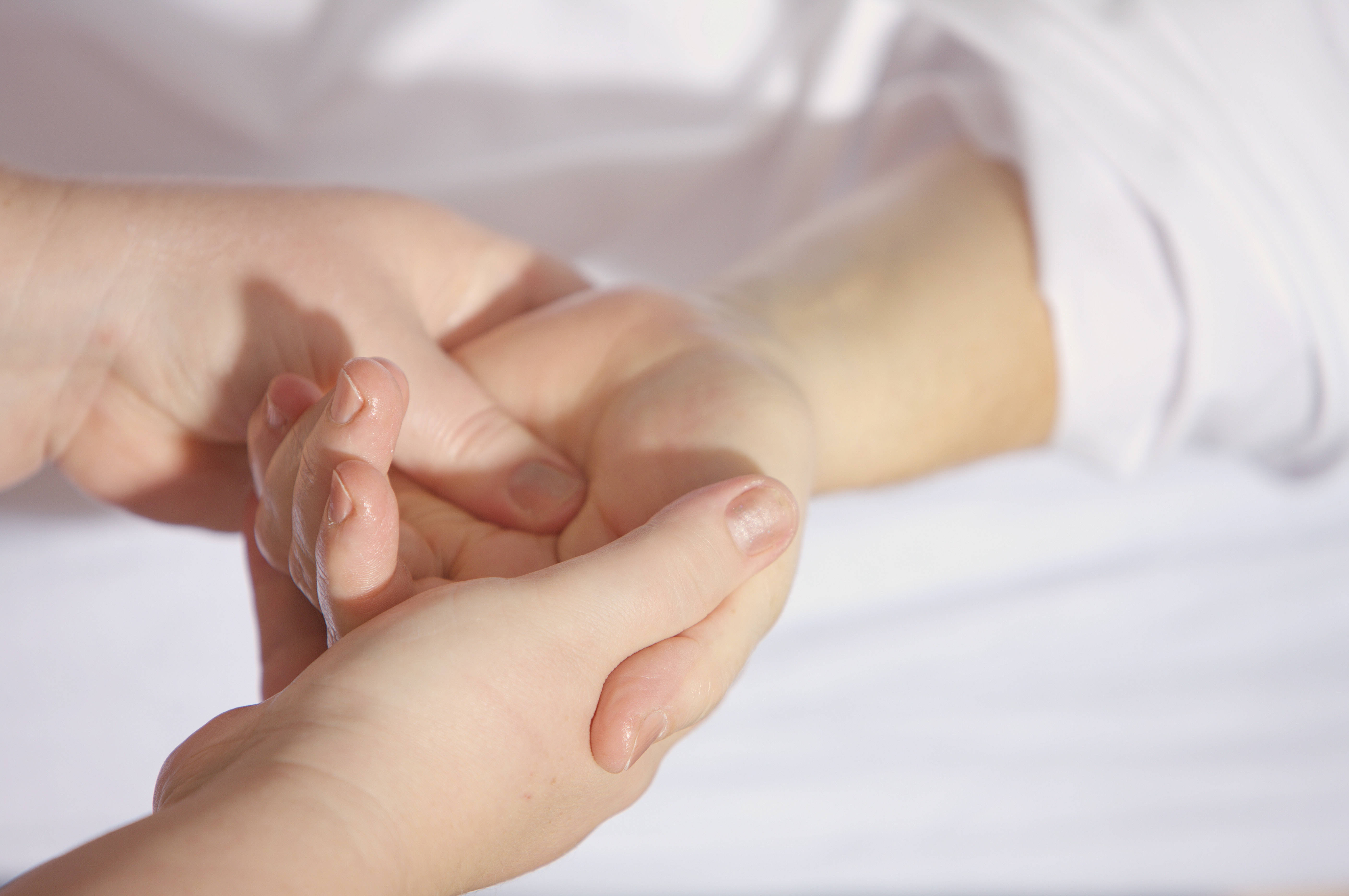 Massage 桌布 壁紙 — 柔和的手部按摩，搭配柔軟白色亞麻布和自然光，凸顯肌膚質感和護理。