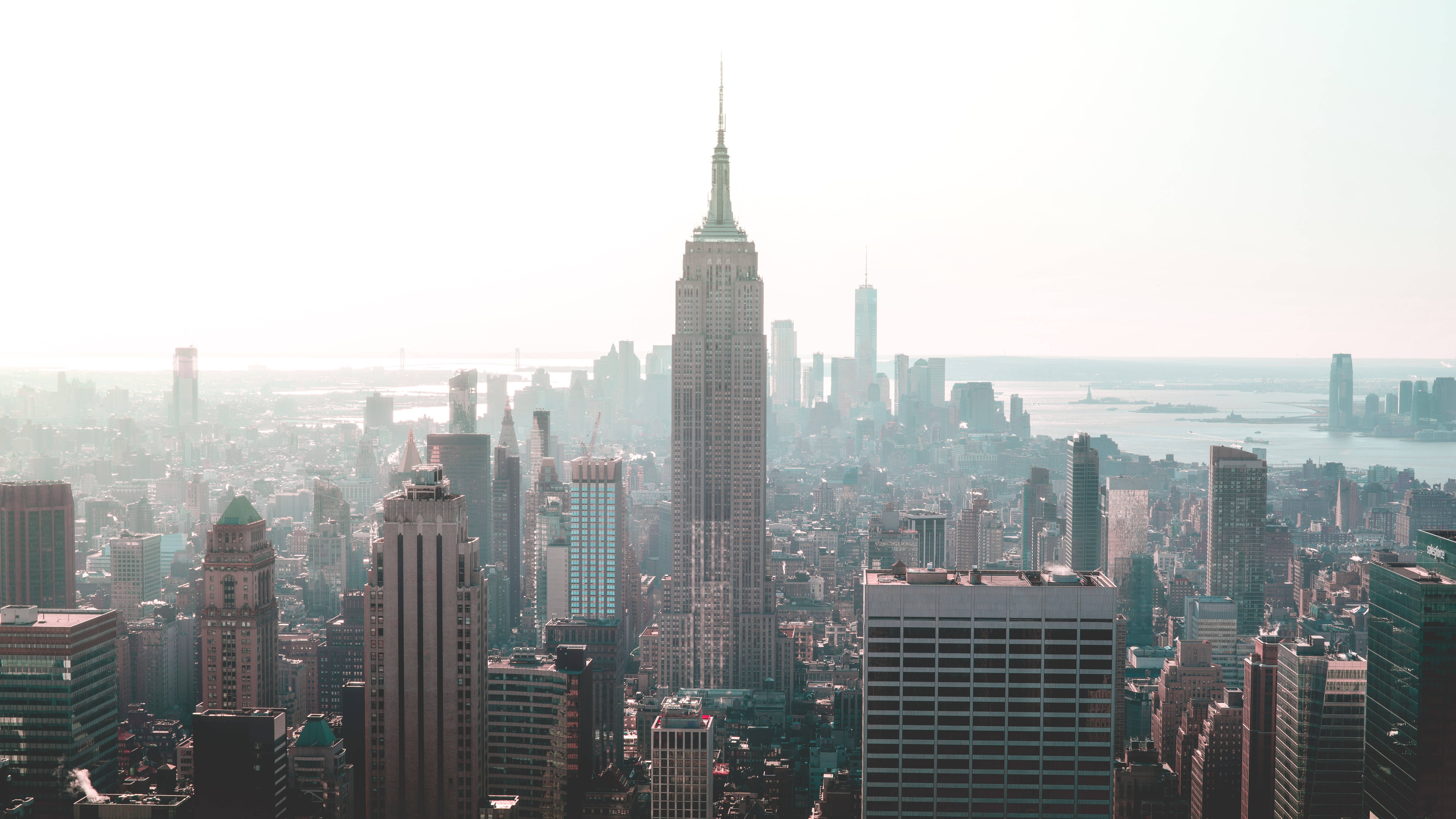 empire state 桌布 壁紙 — 柔和的晨光下，以帝國大廈為主導的紐約市天際線的朦朧鳥瞰圖。