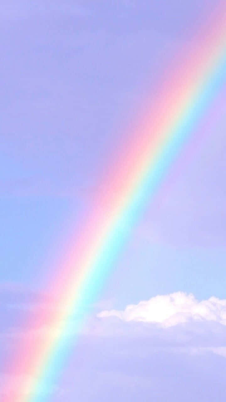 Aesthetic Rainbow Mobile 桌布 壁紙 — 柔和的粉彩彩虹優雅地拱起在寧靜的薰衣草色天空上，下方有縷縷輕雲。