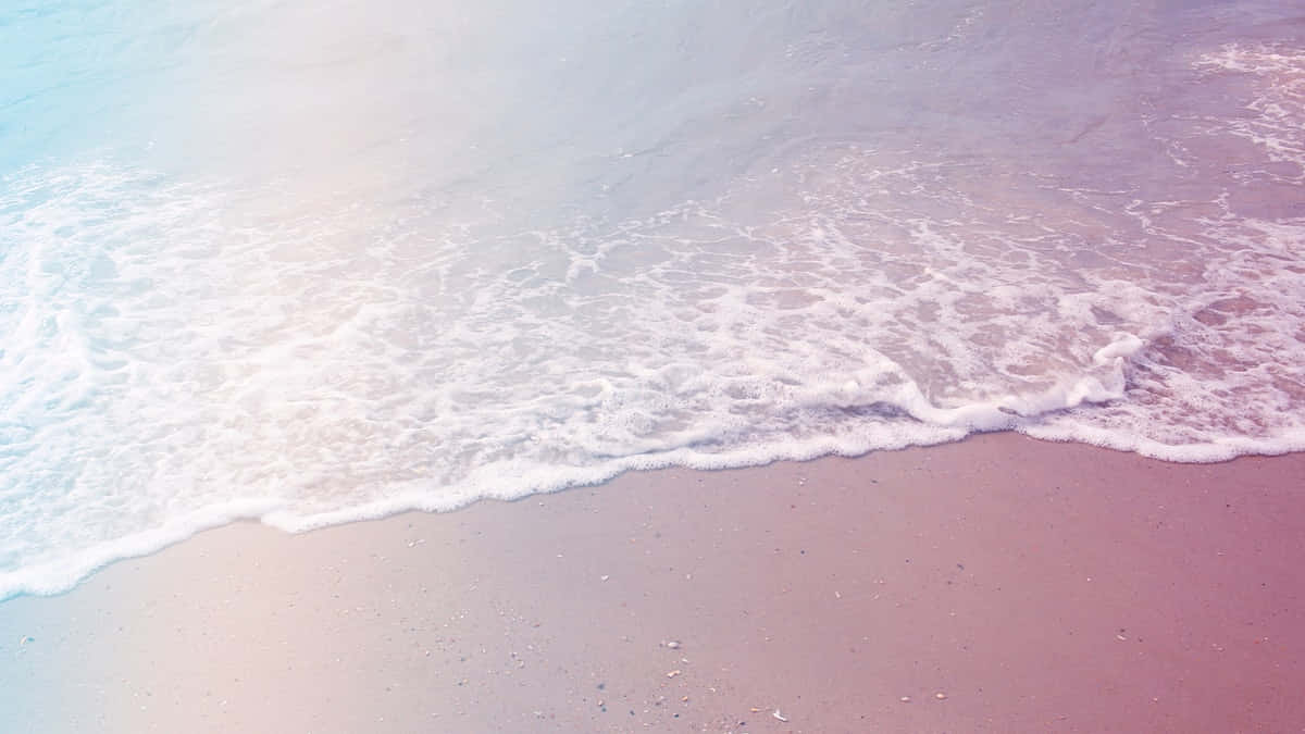 Aesthetic Beach 桌布 壁紙 — 柔和的粉彩波浪在朦朧的天空下輕輕拍打粉紅色的沙灘。