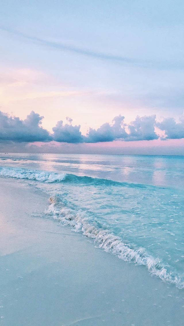 雲朵 桌布 壁紙 — 柔和的粉彩波浪輕輕拍打寧靜的海灘，在夢幻的暮色天空下，有粉紅色和藍色的雲。