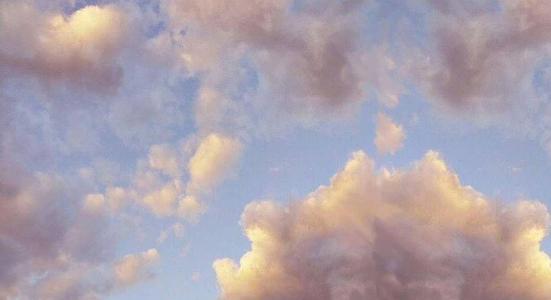 桌布 壁紙 — 柔和的粉彩雲在日落時分飄過一片寧靜的天空，散發著溫暖的金色和薰衣草色調。