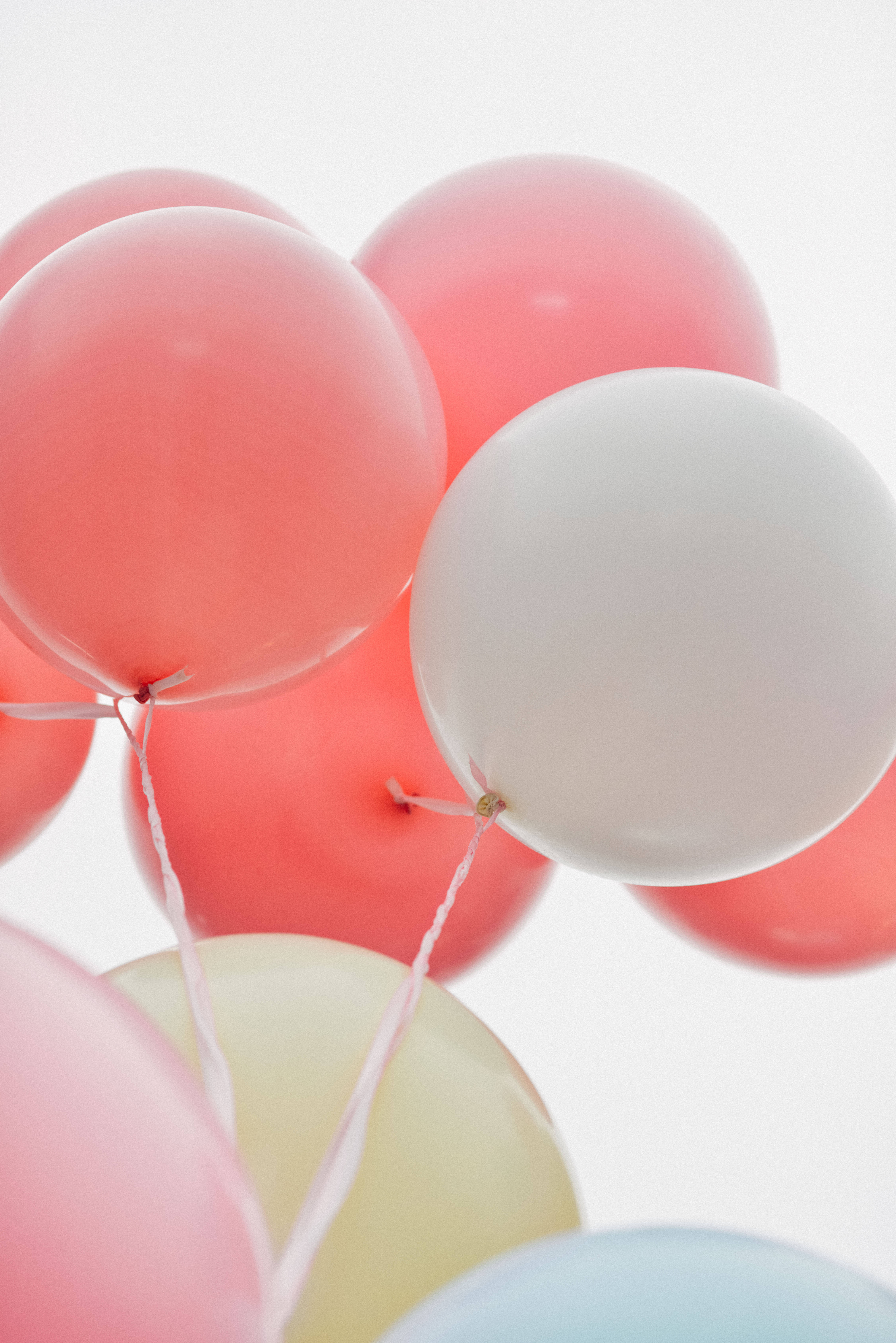 Balloon 桌布 壁紙 — 柔和的粉紅色、白色和淡黃色氣球在明亮的白色背景上輕輕飄浮。