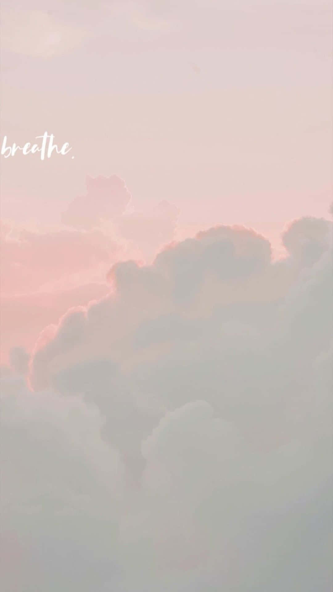 Angel Aesthetic Clouds 桌布 壁紙 — 柔和的粉紅色和灰色雲朵在寧靜的天空中飄浮，breathe 這個字以白色微妙地書寫。
