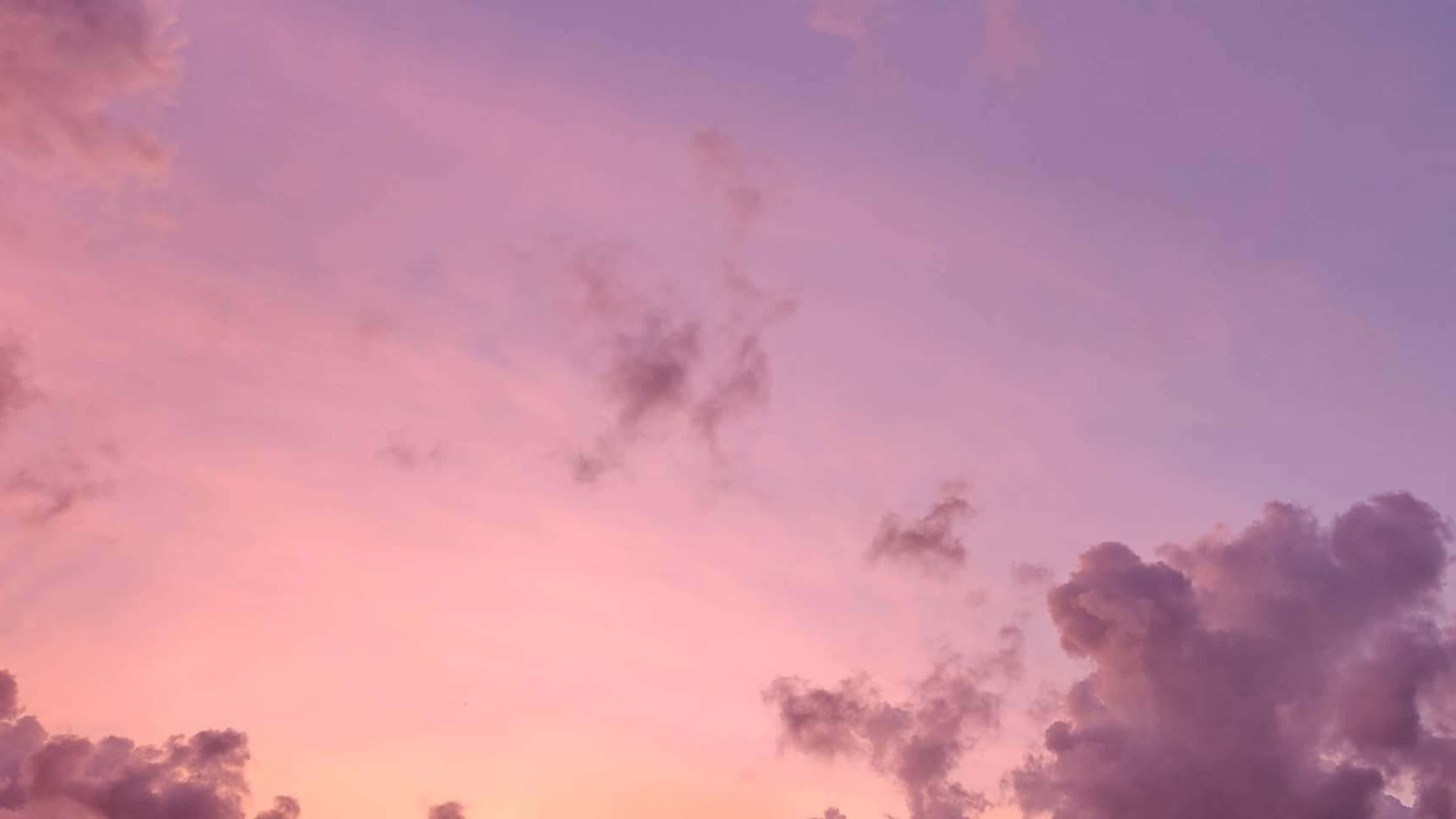 美學雲朵 桌布 壁紙 — 柔和的粉紅色和紫色雲彩在暮色天空中飄移，散發著溫暖的日落色調。