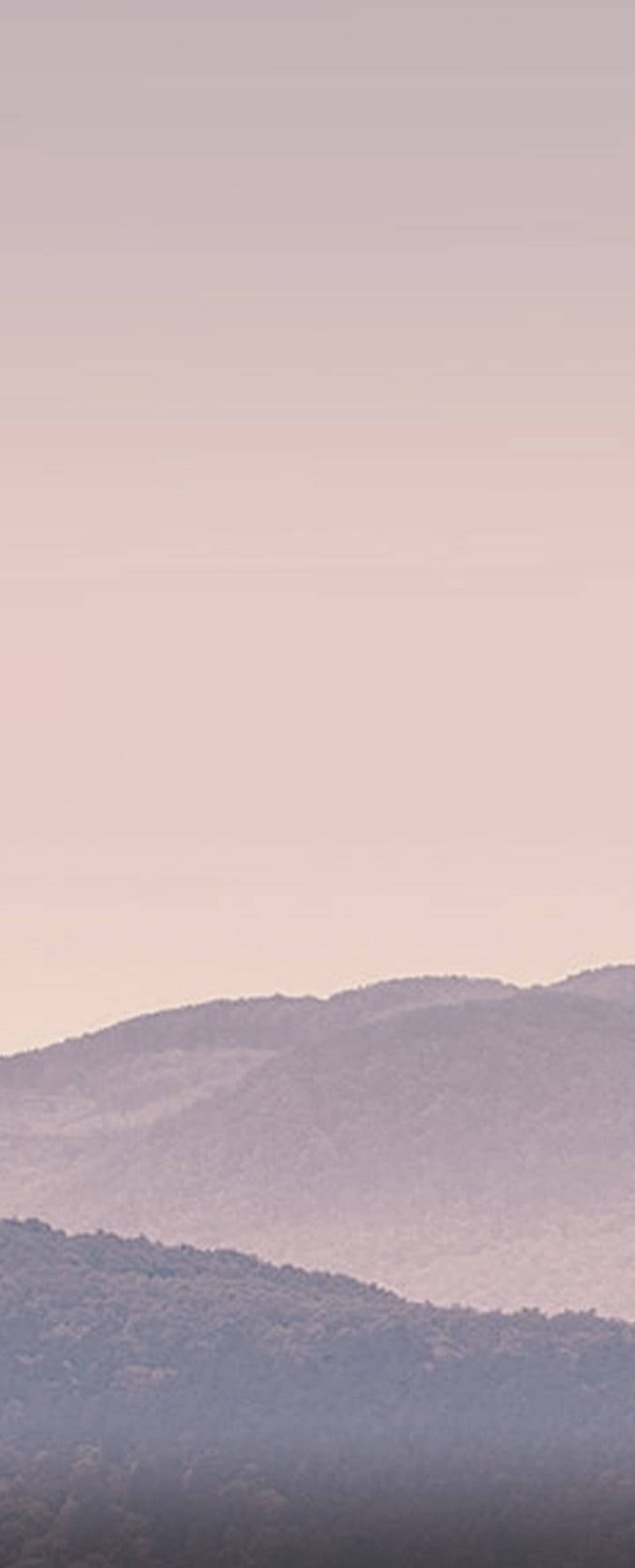 Themes 桌布 壁紙 — 柔和的粉紅色和薰衣草色山脈在朦朧的暮色天空下逐漸消失在霧中。