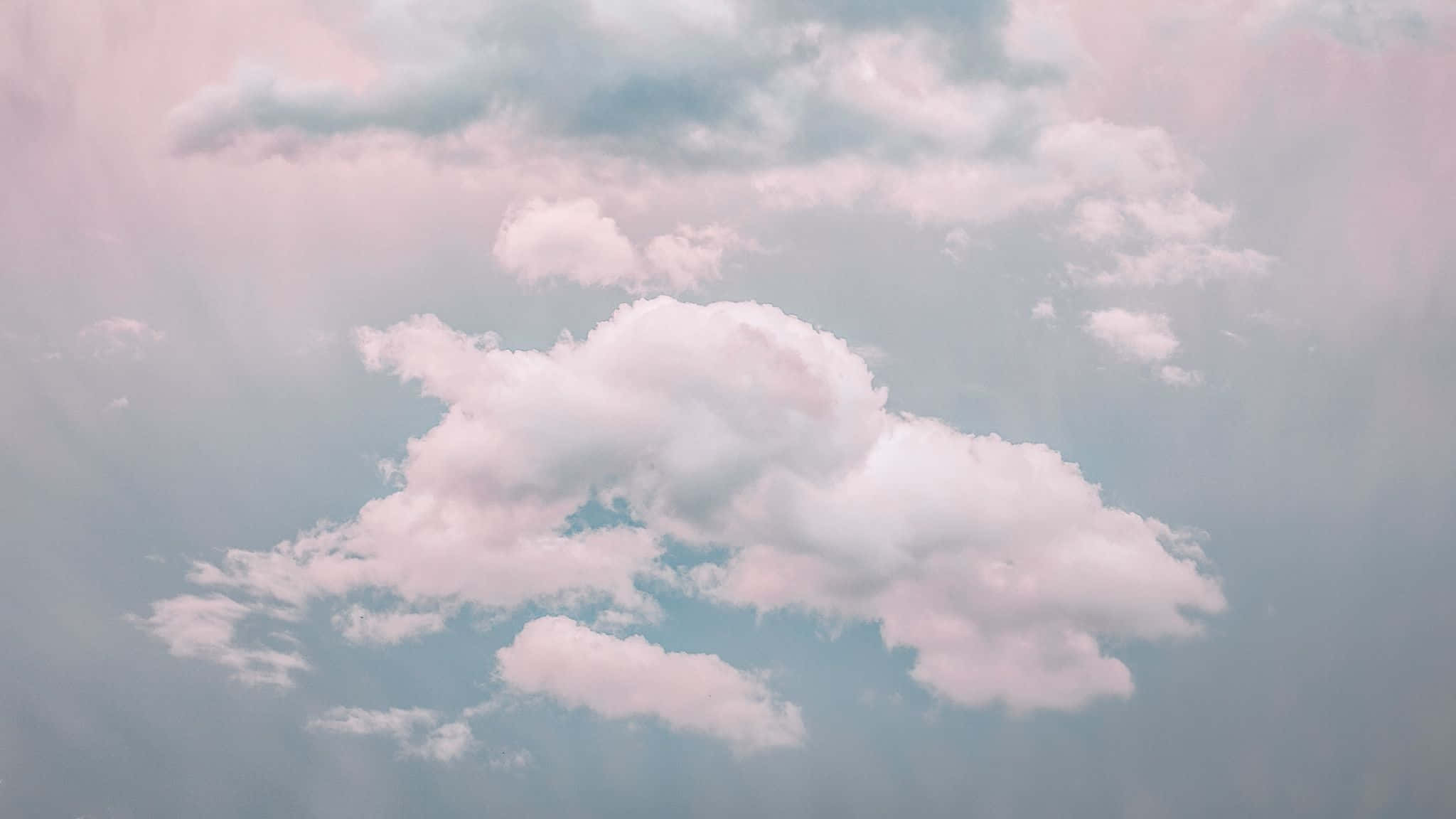 pastel 桌布 壁紙 — 柔和的粉紅色和藍色雲朵在寧靜的天空中飄移，柔和的光線穿透而過。