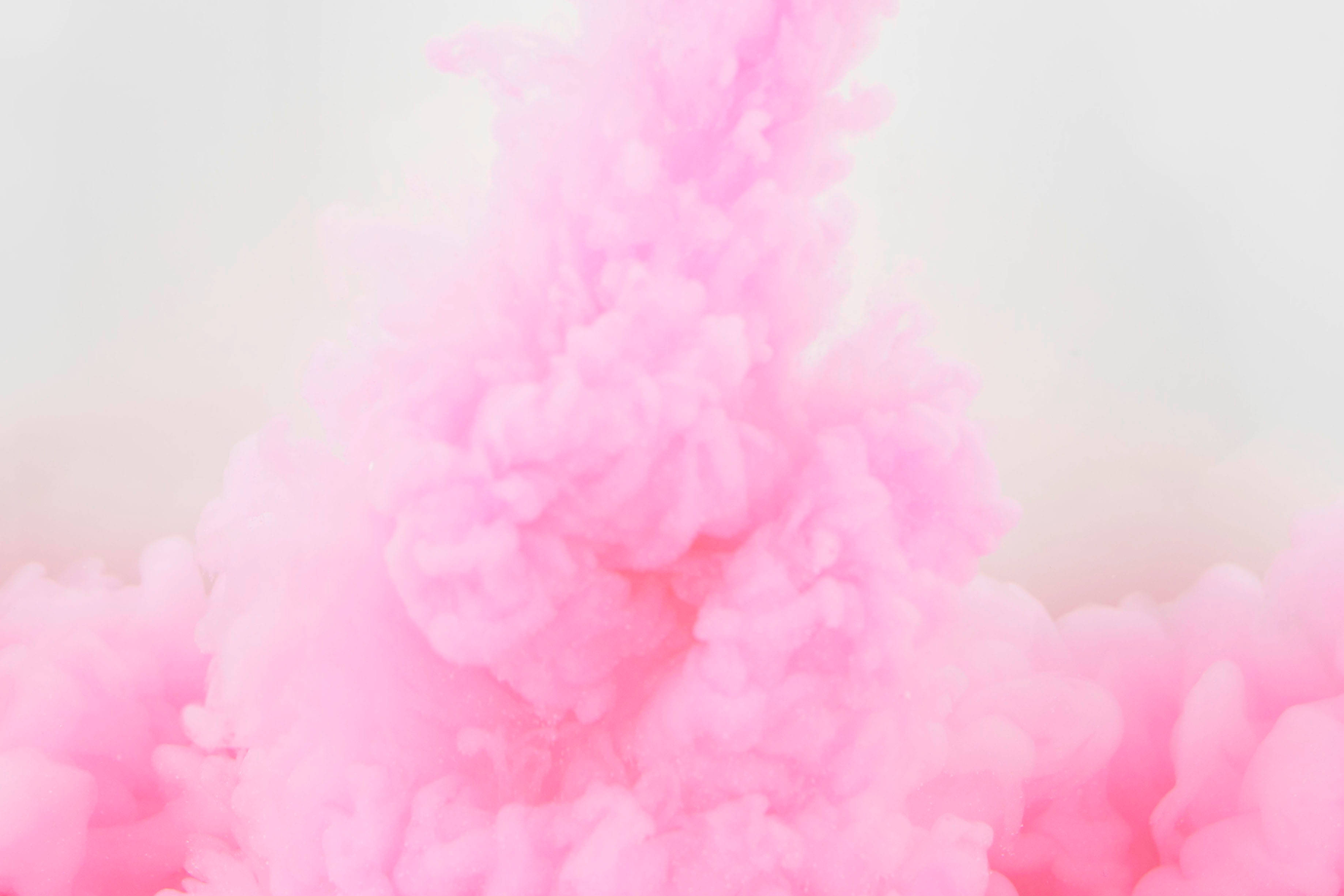 Smoke HD 桌布 壁紙 — 柔和的粉紅色墨水漩渦在淺色背景上以流暢的抽象動態戲劇性地旋轉。