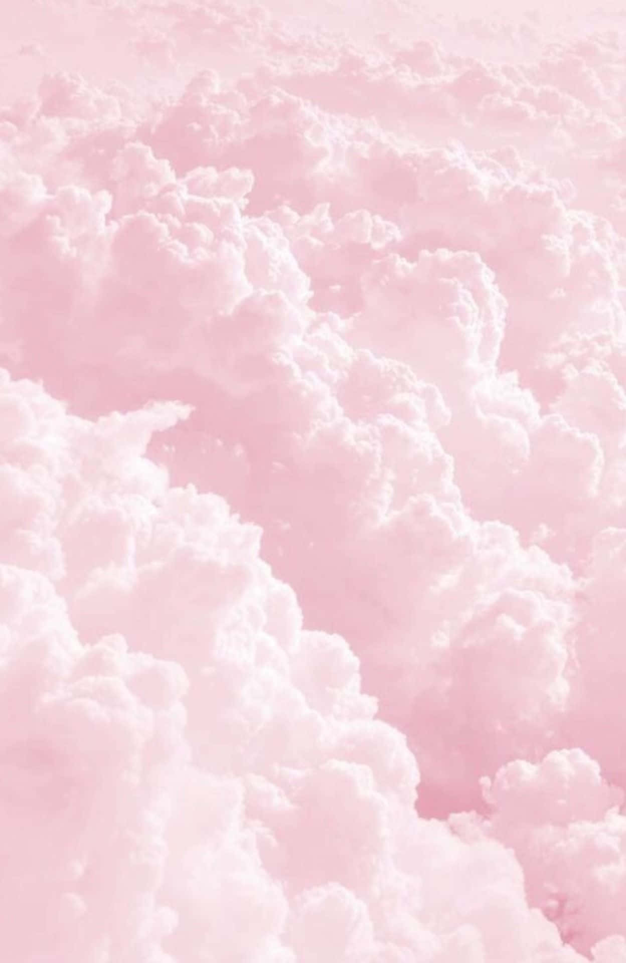 Pink Pastel 桌布 壁紙 — 柔和的粉紅色天空，充滿了蓬鬆的棉花糖雲朵，輕輕飄過。
