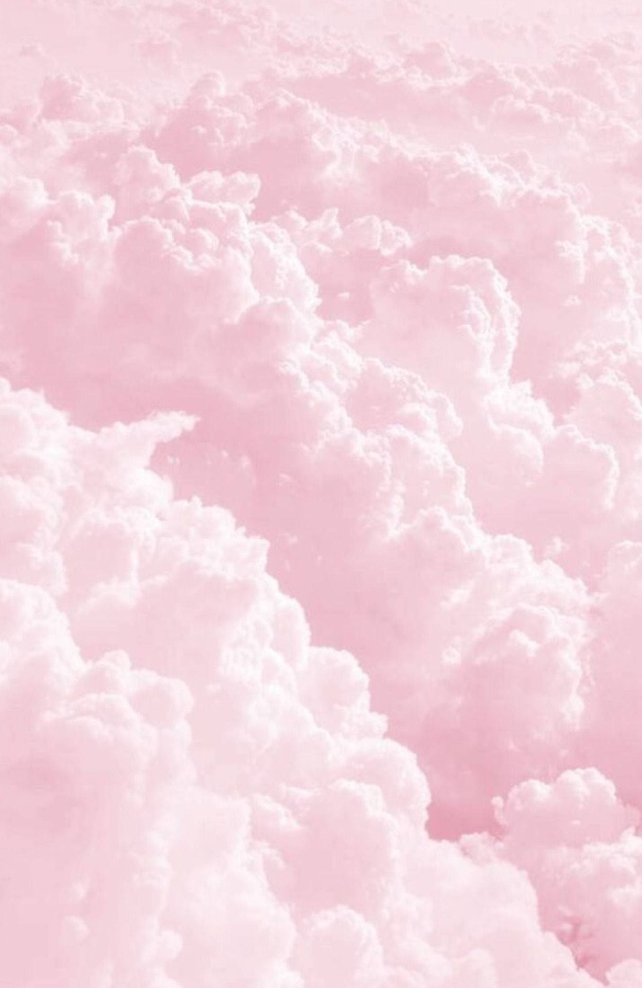 Pastel Pink iPhone 桌布 壁紙 — 柔和的粉紅色天空佈滿蓬鬆的白雲，營造出夢幻般的粉彩氛圍。