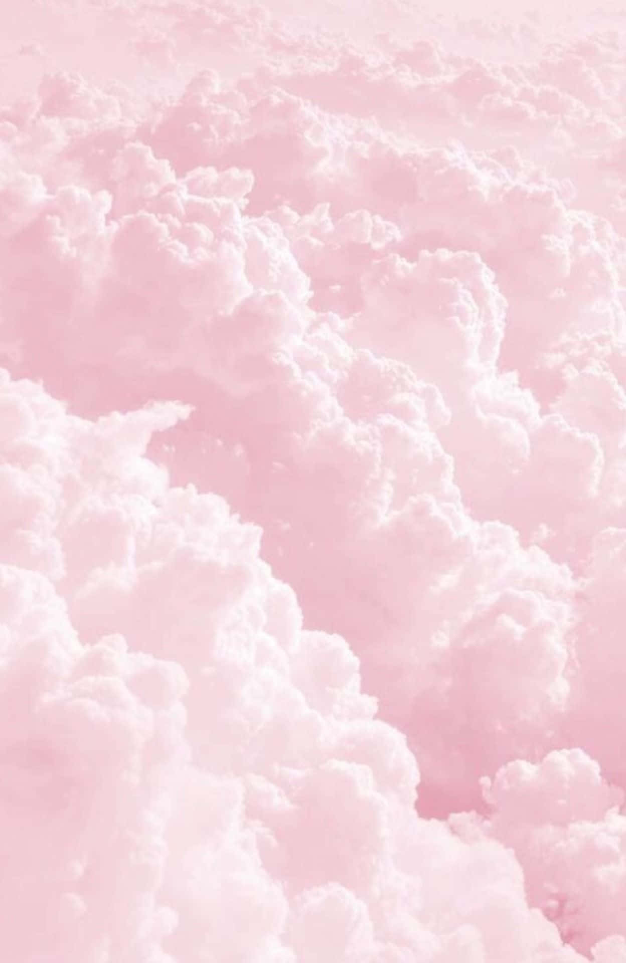 Pink Phone 桌布 壁紙 — 柔和的粉紅色天空充滿蓬鬆的白雲，營造出夢幻般的粉彩氛圍。