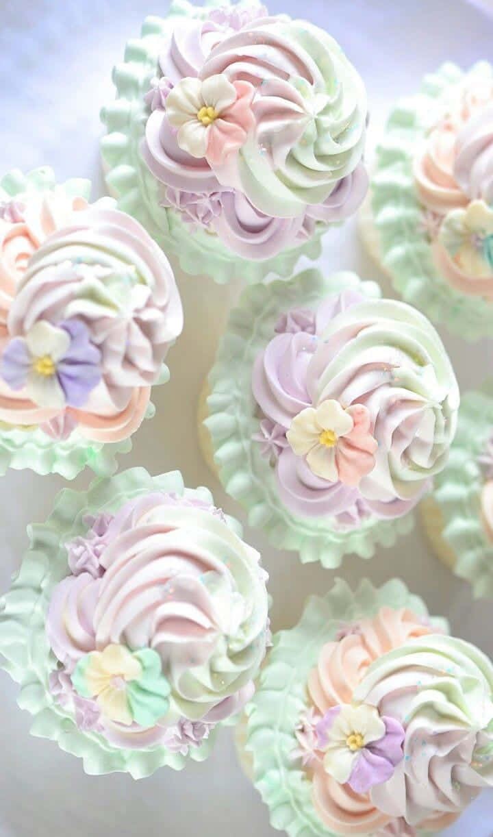 Spring Desserts 桌布 壁紙 — 柔和的薄荷、蜜桃、薰衣草和奶油色調的漩渦紙杯蛋糕，上面綴以精緻的糖花。