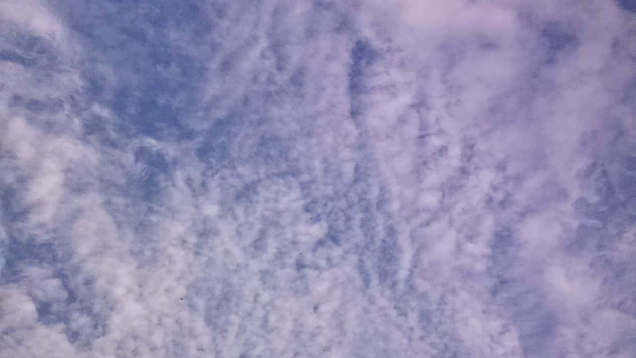 SKY-4 壁紙 — 柔和的薰衣草色和淡藍色雲朵在寧靜的天空中飄動，形成精緻的縷縷圖案。