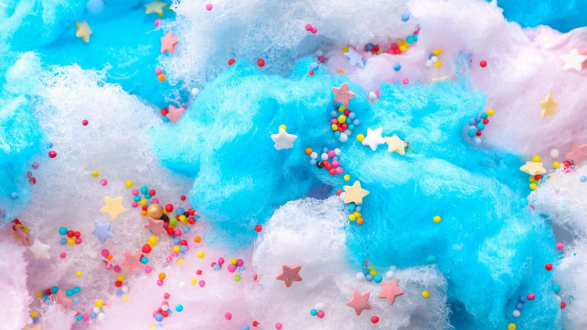 Cotton Candy 桌布 壁紙 — 柔和的藍色和粉紅色棉花糖雲，點綴著彩色糖粒和星形糖果。