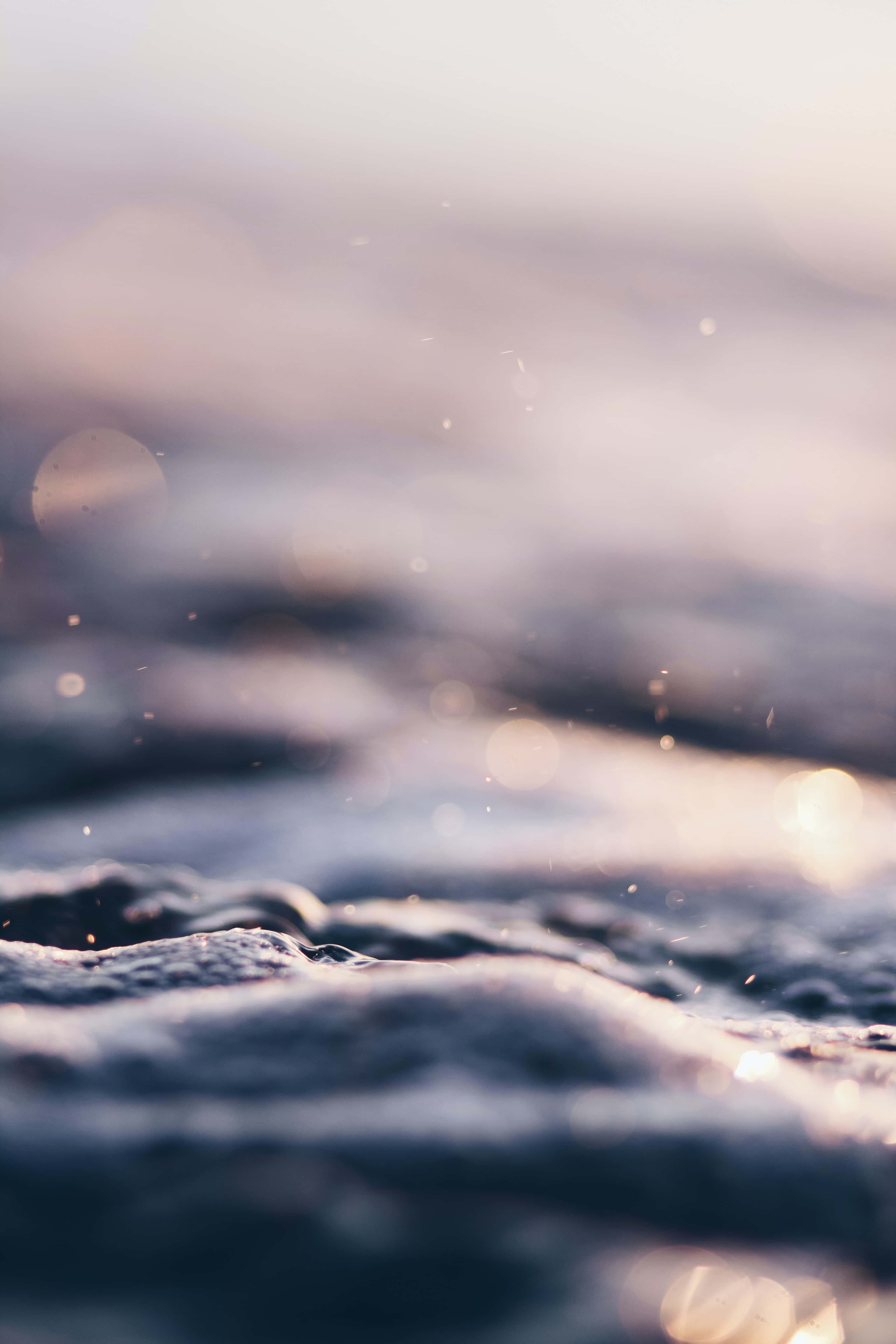 Calming 桌布 壁紙 — 柔和的金色光線下，溫柔的海浪泛起漣漪，帶有閃爍的散景和淺景深。