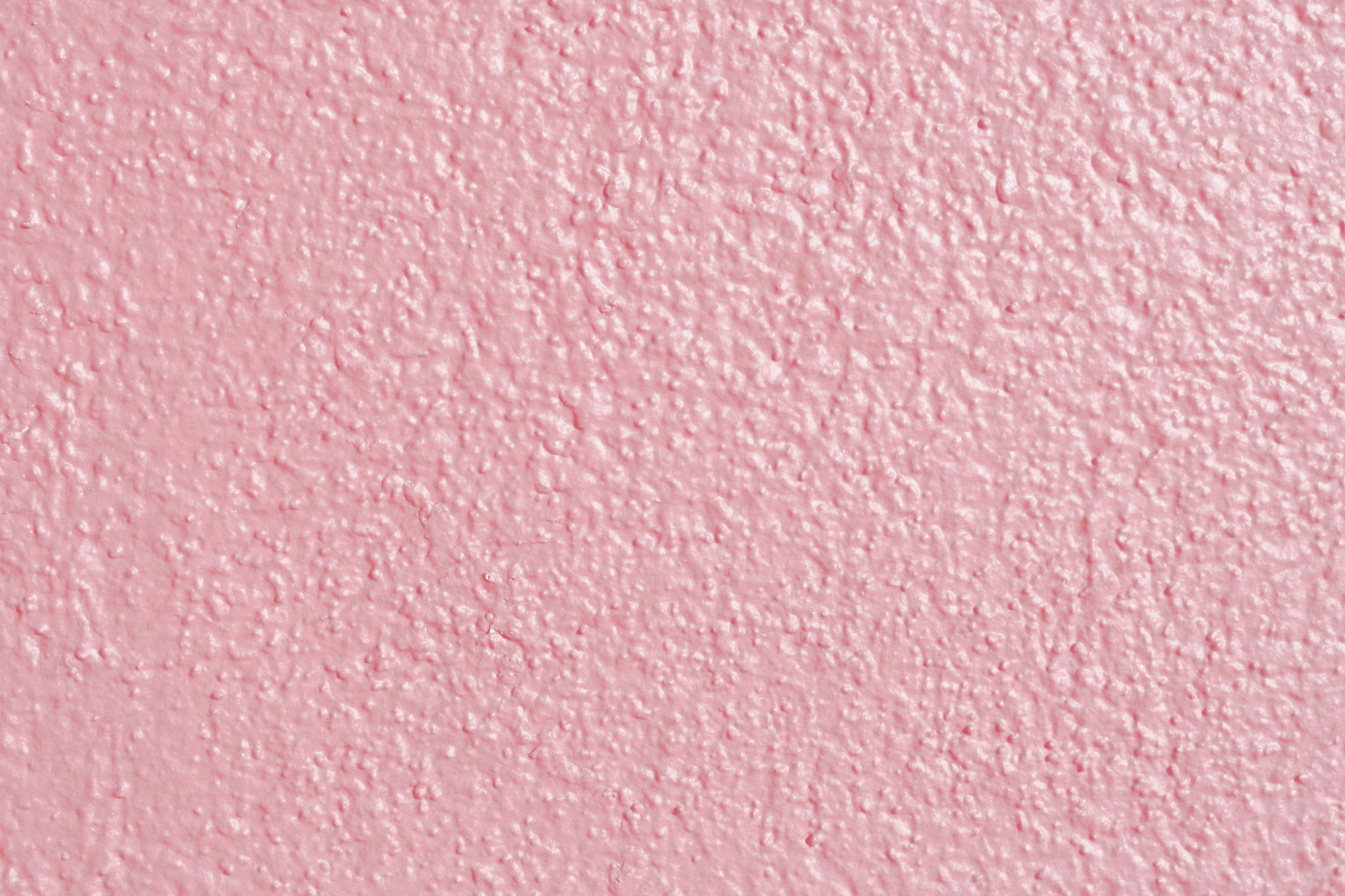 Pink Wall 桌布 壁紙 — 柔和粉紅色紋理牆壁的近距離特寫，表面有凹凸不平的灰泥飾面，光線均勻。