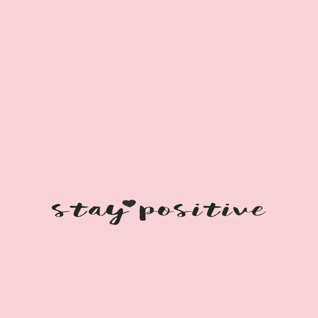 正向 桌布 壁紙 — 柔和粉紅色背景，黑色草書文字寫著「stay positive」，並以心形取代字母「o」。