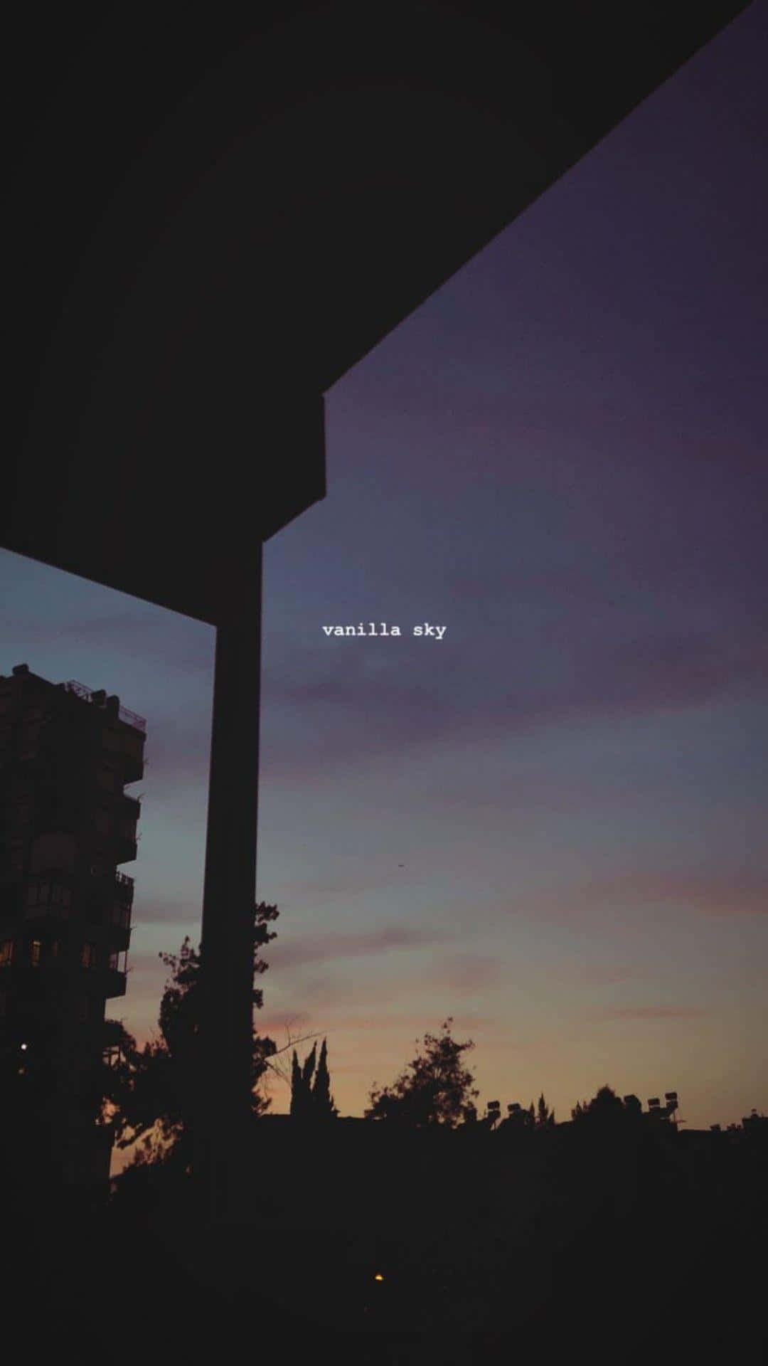 sadness 桌布 壁紙 — 柔和紫色和橙色色調的暮色天空，被黑暗的建築輪廓和遠處的城市燈光所框住。
