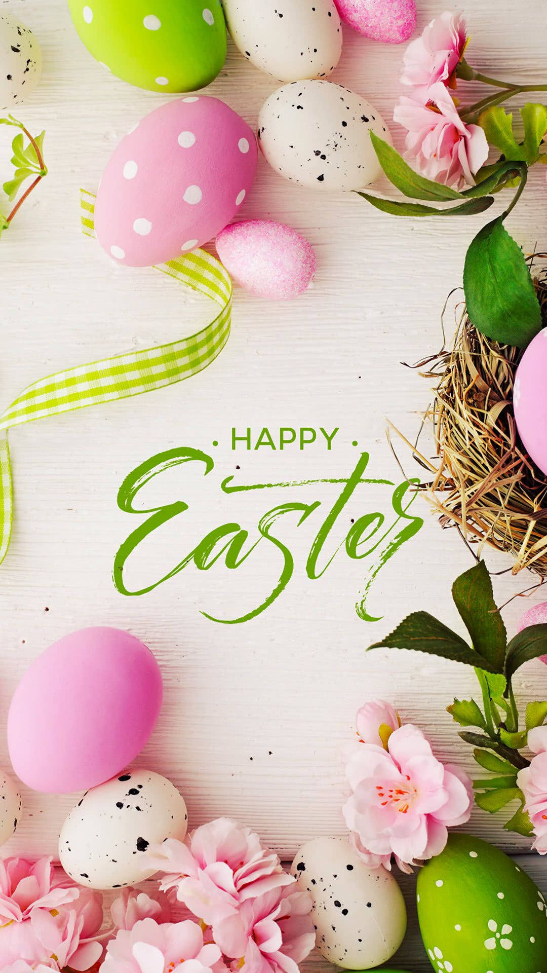 Easter iPhone 桌布 壁紙 — 柔和色調的復活節蛋和粉紅色花朵排列在白色木質表面上，配有綠色絲帶和一個巢。