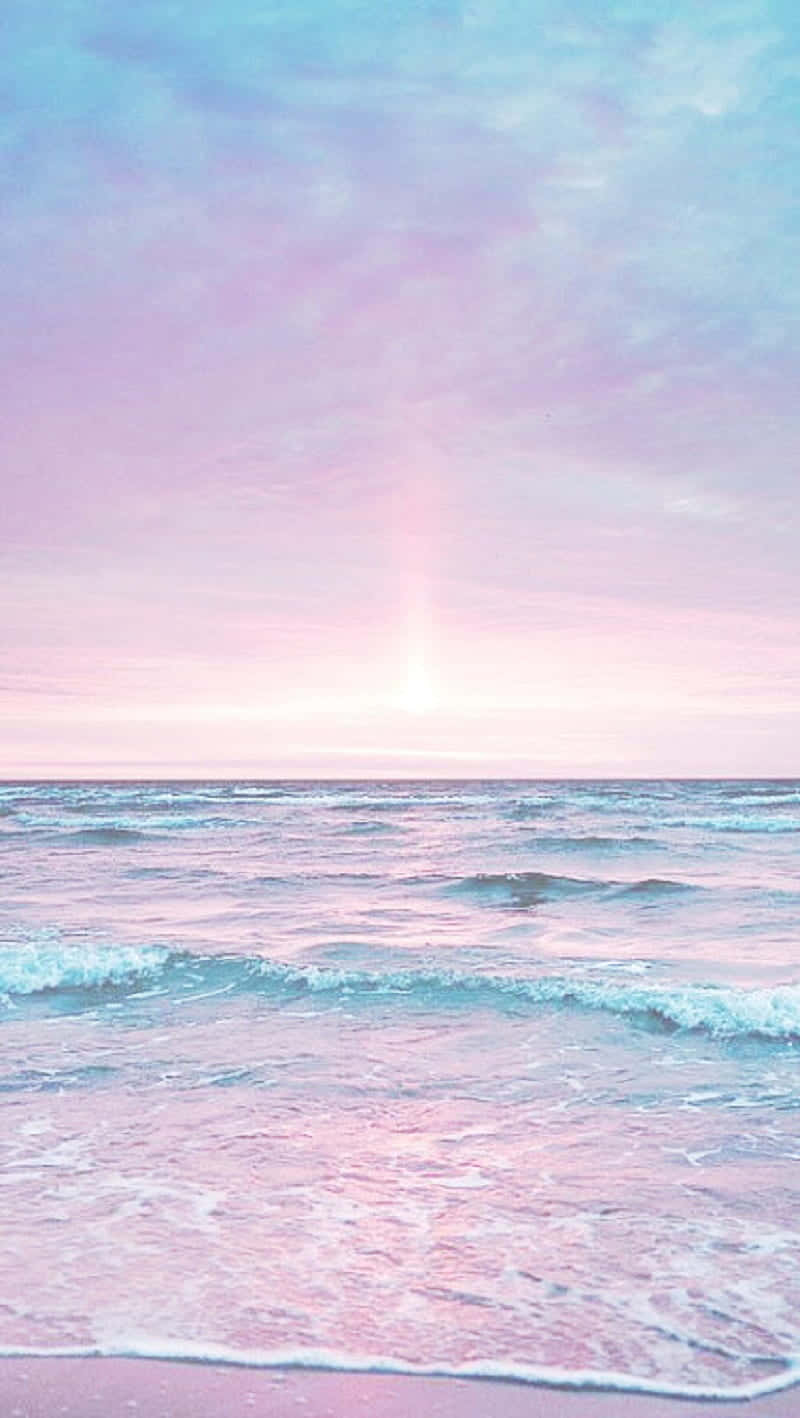 Pastel Beach 桌布 壁紙 — 柔和雲朵下，夢幻暮色天空中，粉彩粉紅與藍色波浪輕輕拍打岸邊。