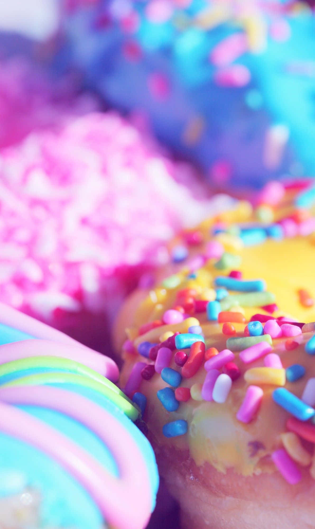 doughnut 桌布 壁紙 — 柔焦拍攝下，色彩繽紛的甜甜圈，上面有彩虹糖針和柔和色調的糖霜。