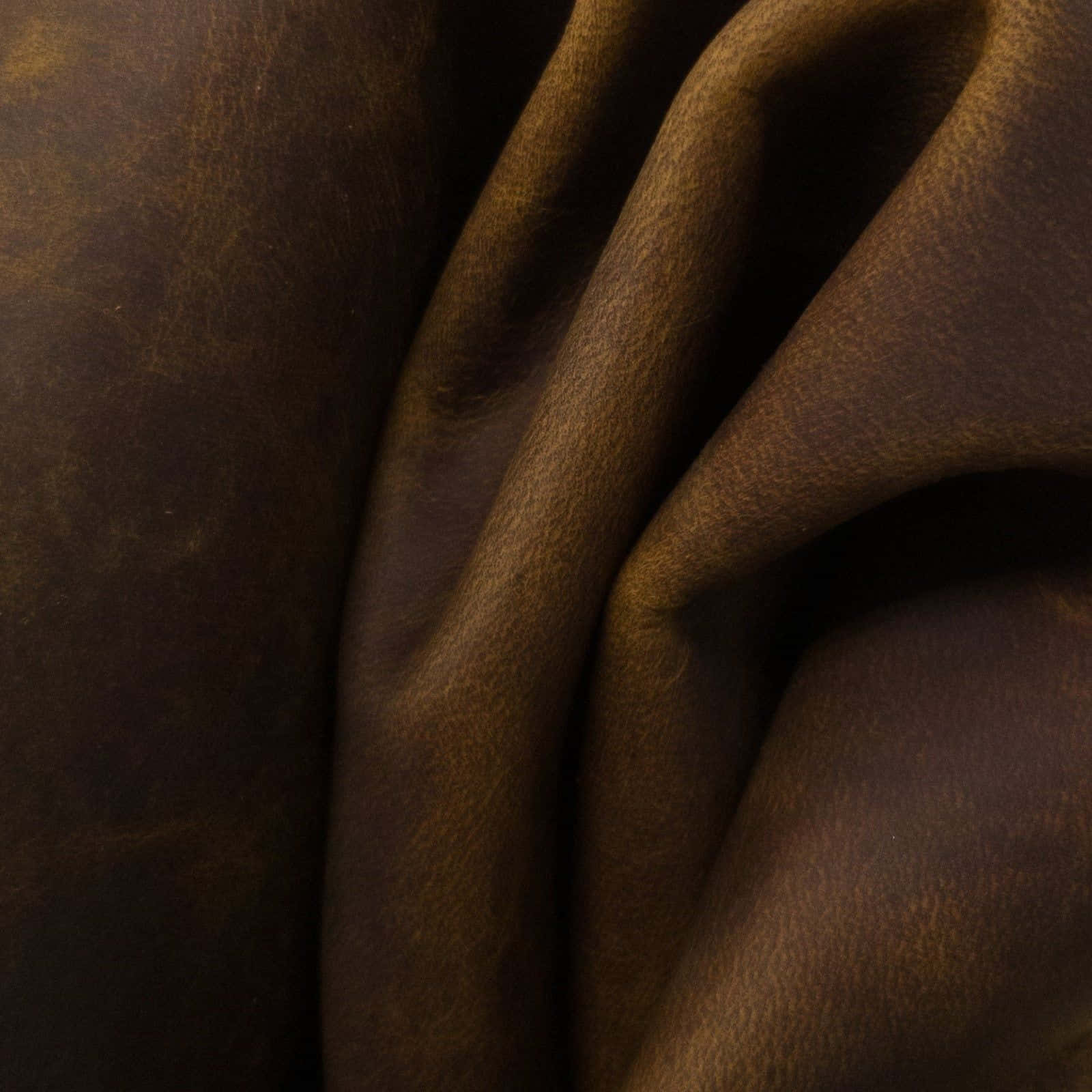 texture 桌布 壁紙 — 柔軟燈光下，深棕色皮革的微距特寫，展現深層皺摺與天然紋理。