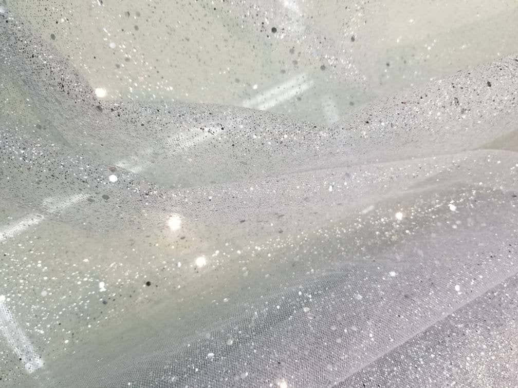 White Glitter 桌布 壁紙 — 柔軟燈光下，精緻白色薄紗布料上散落閃爍亮片的特寫。