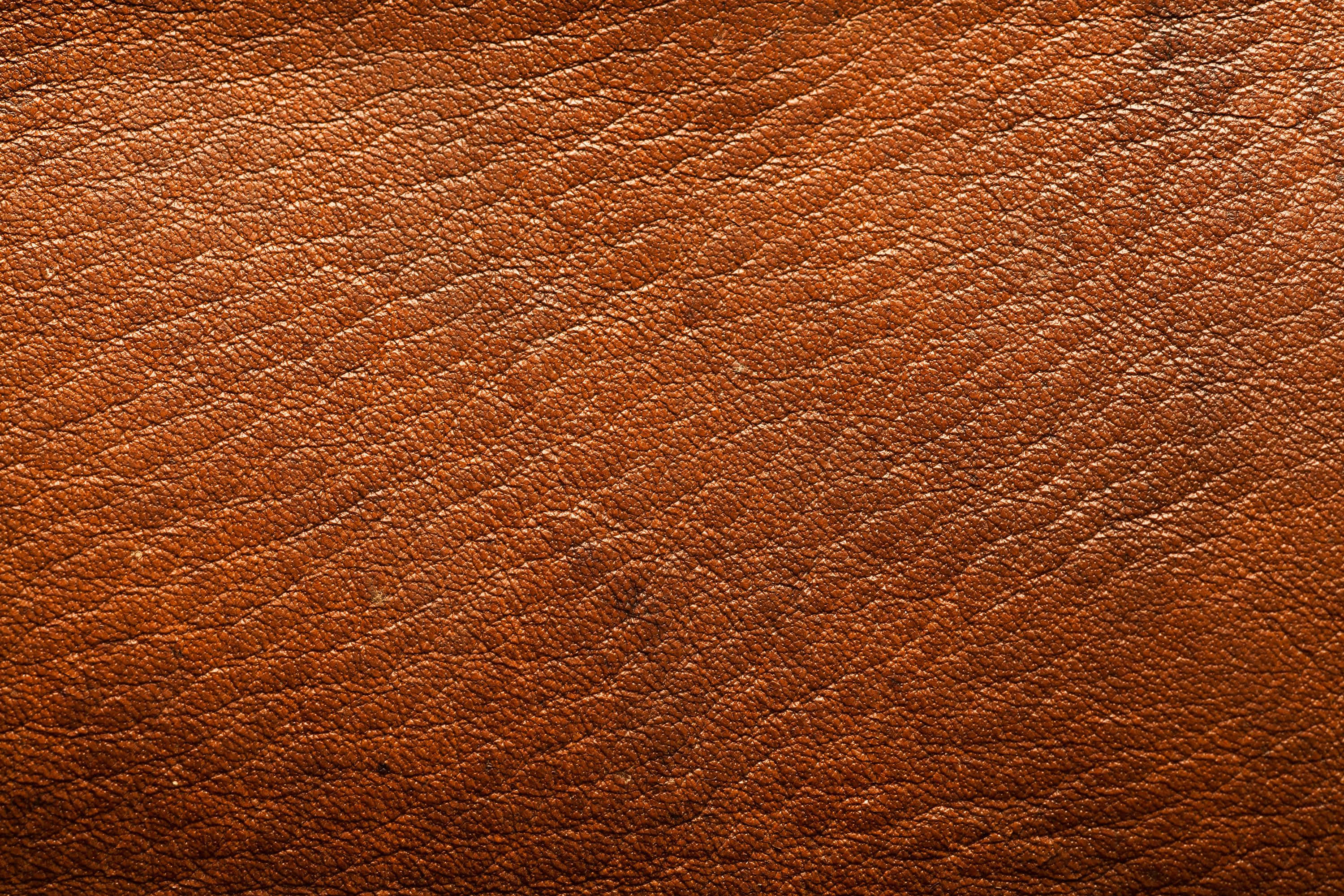 texture 桌布 壁紙 — 柔軟燈光下，豐富棕色皮革的特寫，帶有天然紋理和細微質感變化。