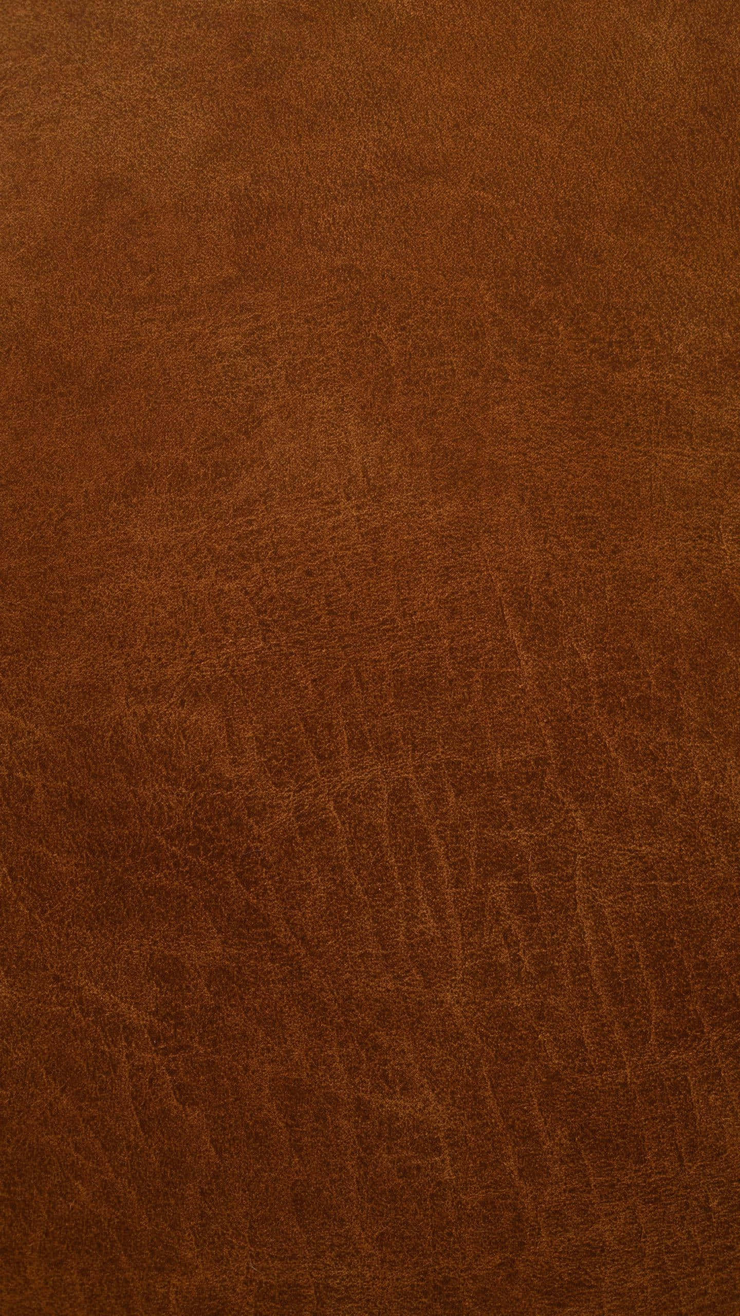 texture 桌布 壁紙 — 柔軟燈光下，豐富棕色皮革的特寫，展現自然紋理和細微皺褶。