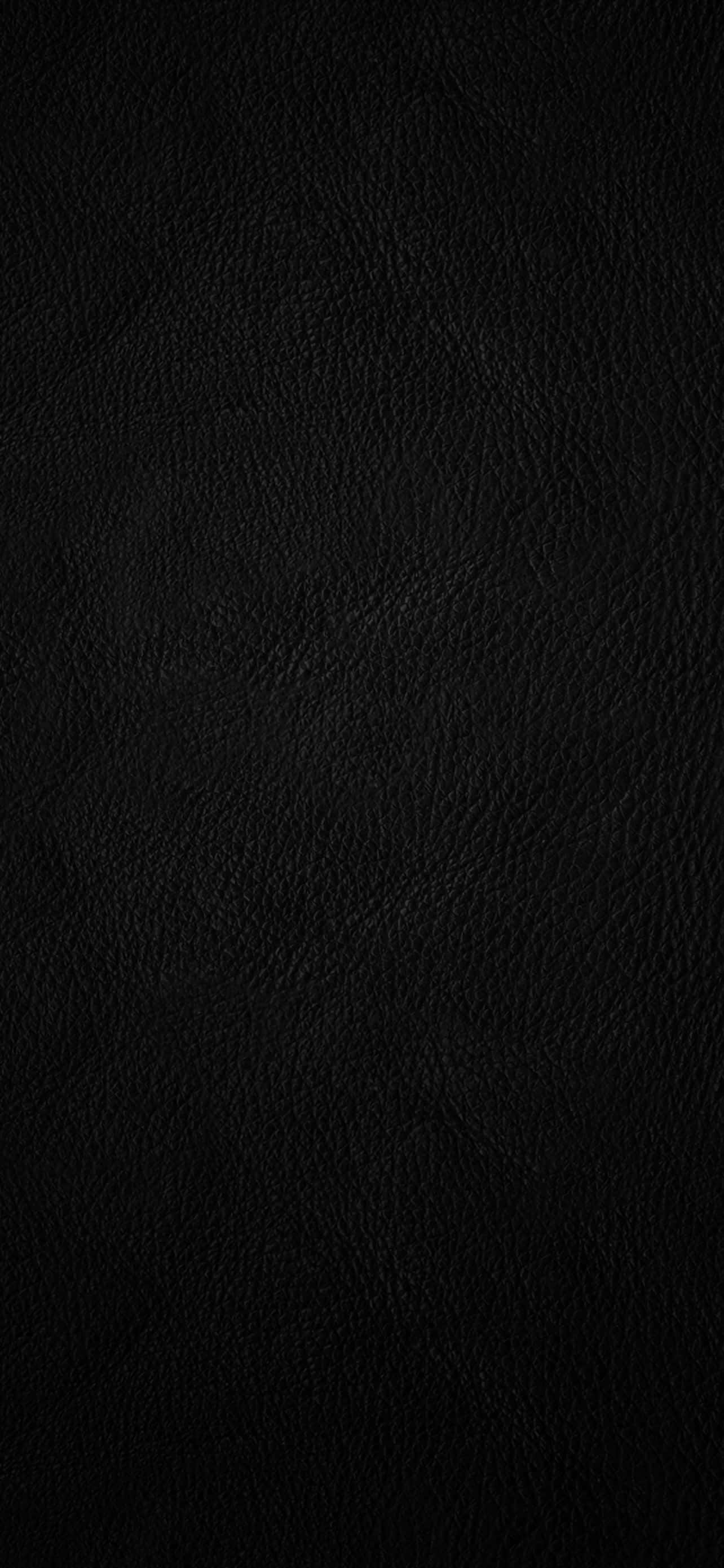 Leather 桌布 壁紙 — 柔軟燈光下光滑黑色皮革表面的特寫，帶有細微的粒面紋理。