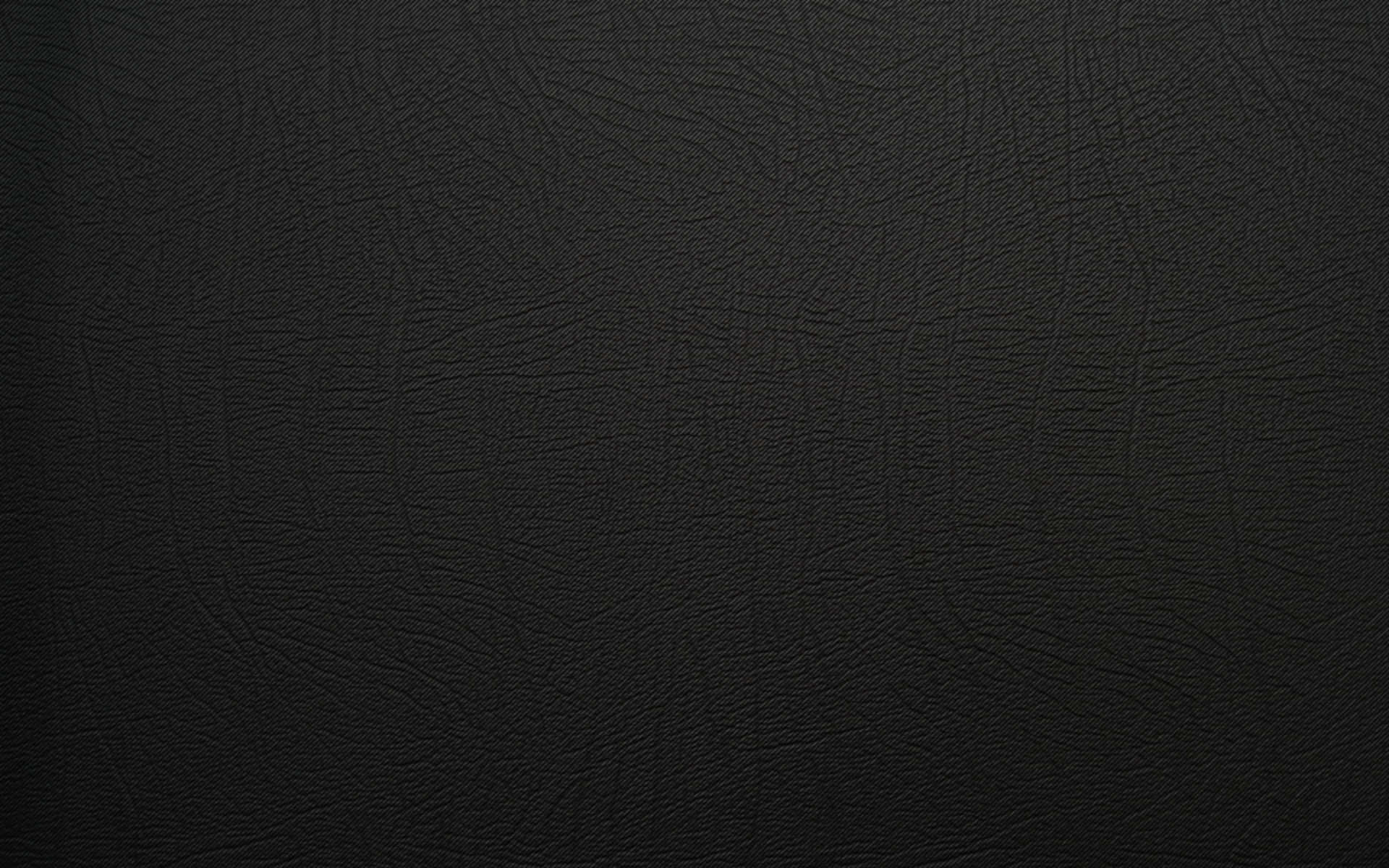 Leather 桌布 壁紙 — 柔軟燈光下光滑黑色皮革表面的特寫，帶有細微的粒面紋理。