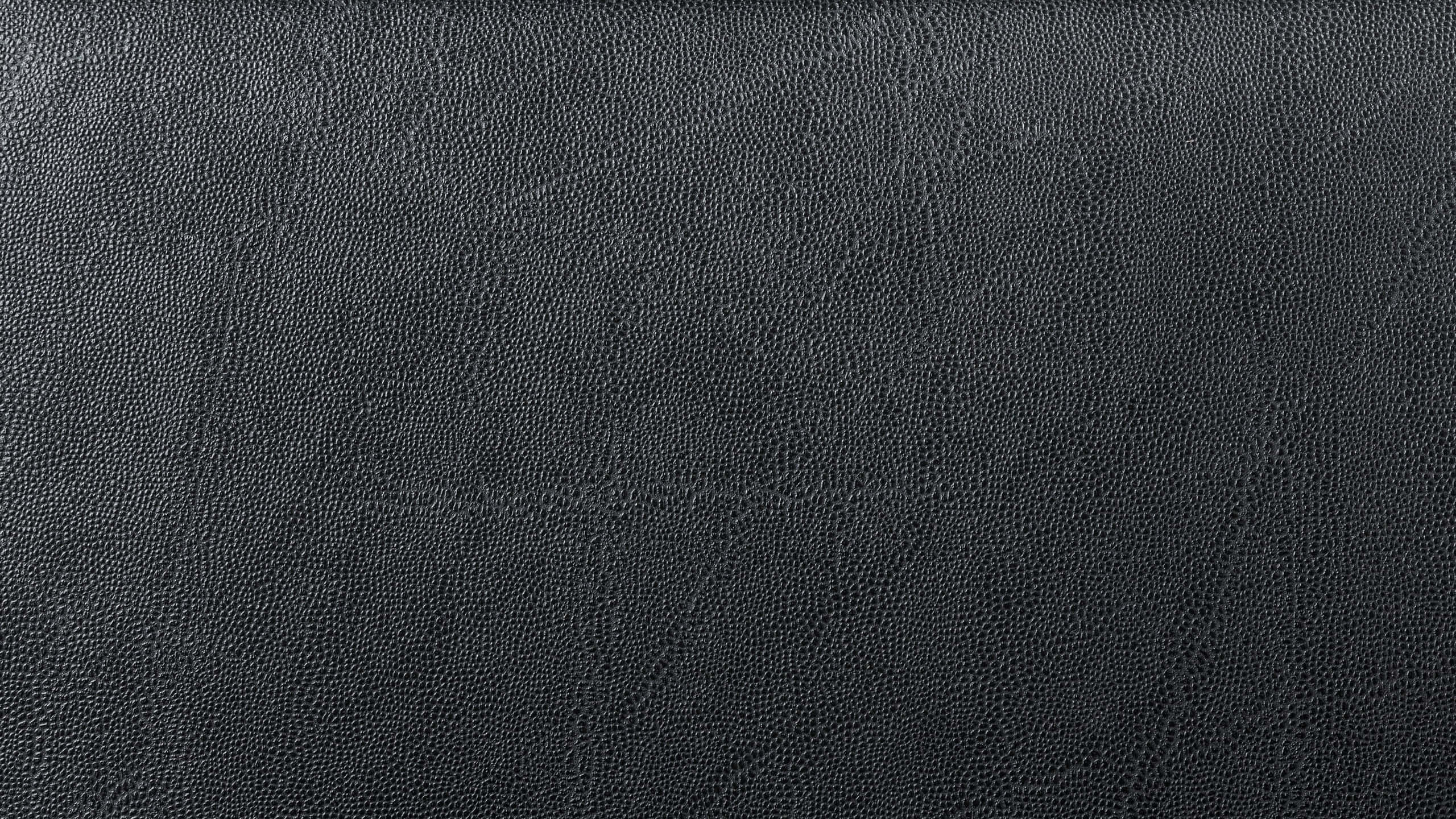 texture 桌布 壁紙 — 柔軟燈光下光滑黑色皮革表面的特寫，帶有細微紋理。