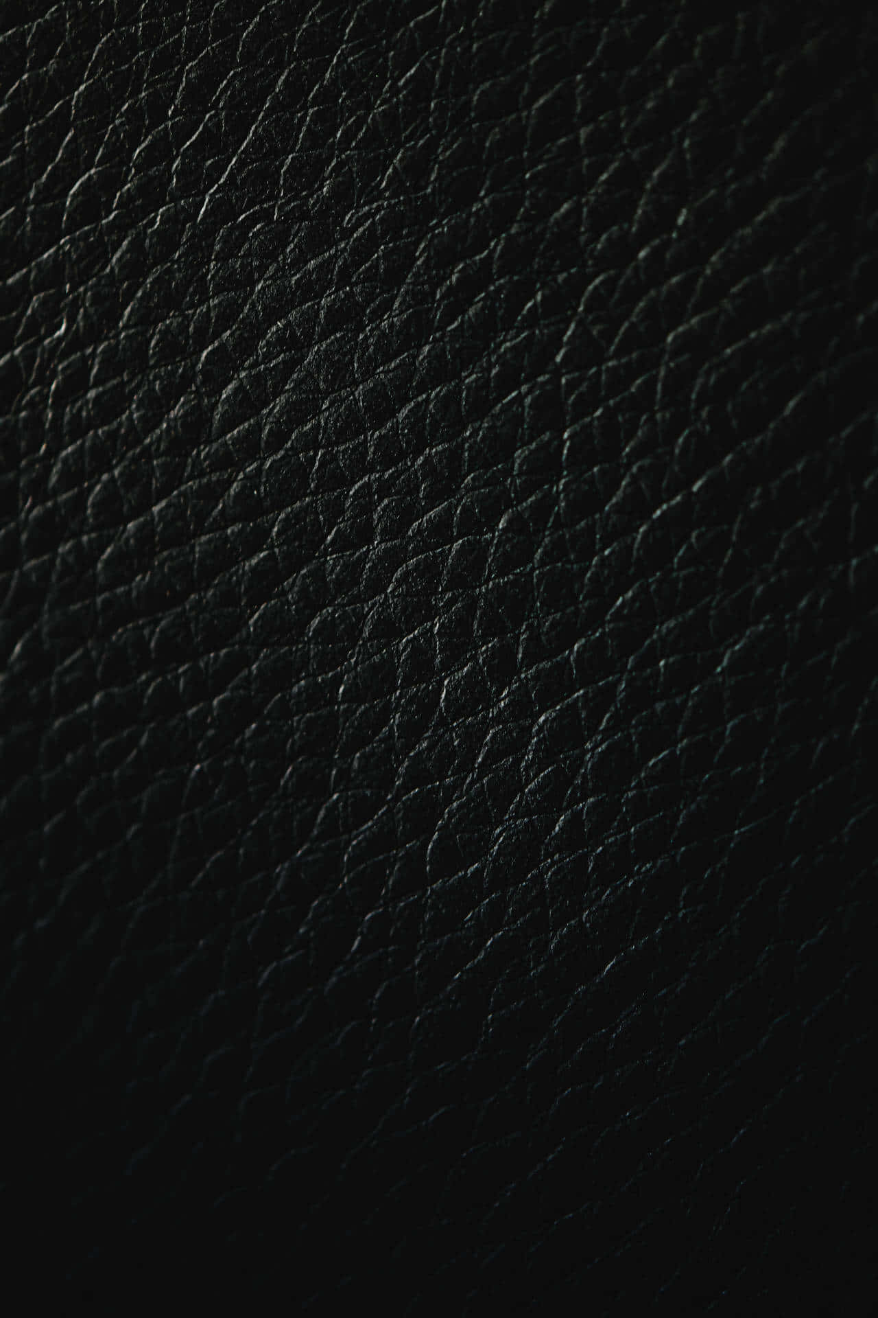 Black Leather 桌布 壁紙 — 柔軟燈光下帶有細微紋理圖案的黑色皮革表面特寫。