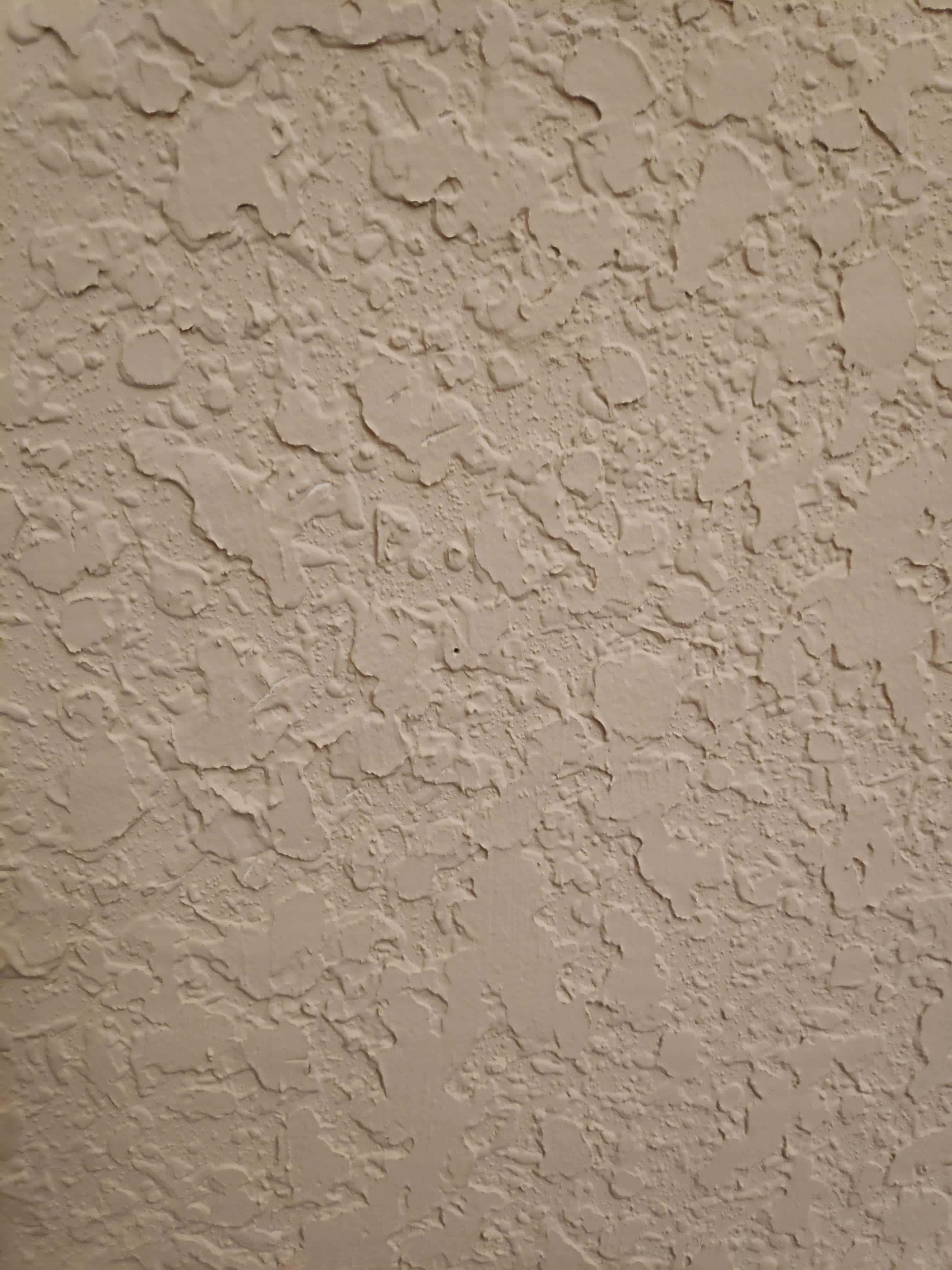 Paint Texture 桌布 壁紙 — 柔軟燈光下的米色灰泥牆特寫，表面粗糙不平，帶有細微裂紋。