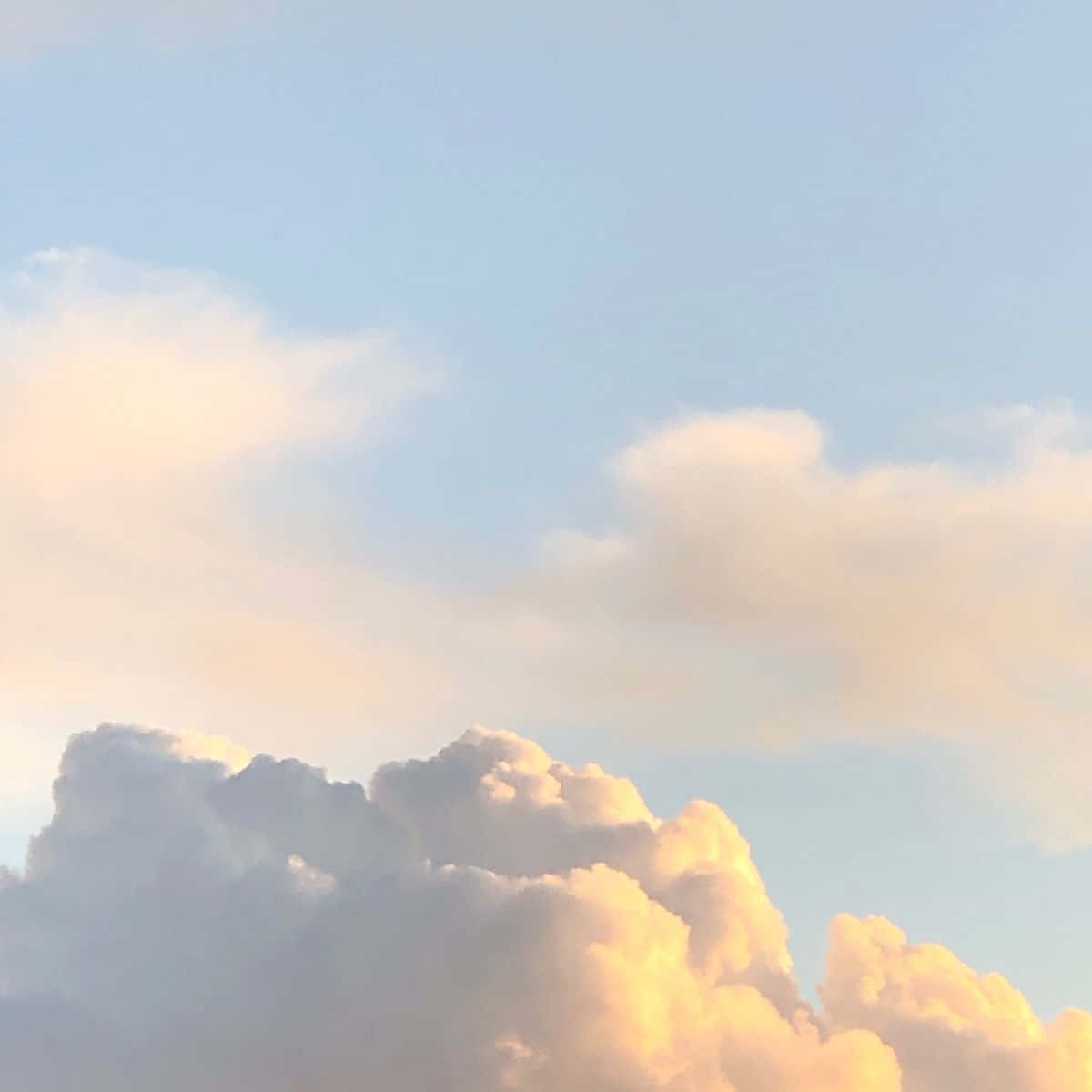 雲朵 桌布 壁紙 — 柔軟的棉絮狀雲朵在日落時分，在淡藍色的天空中閃耀著金色光芒。