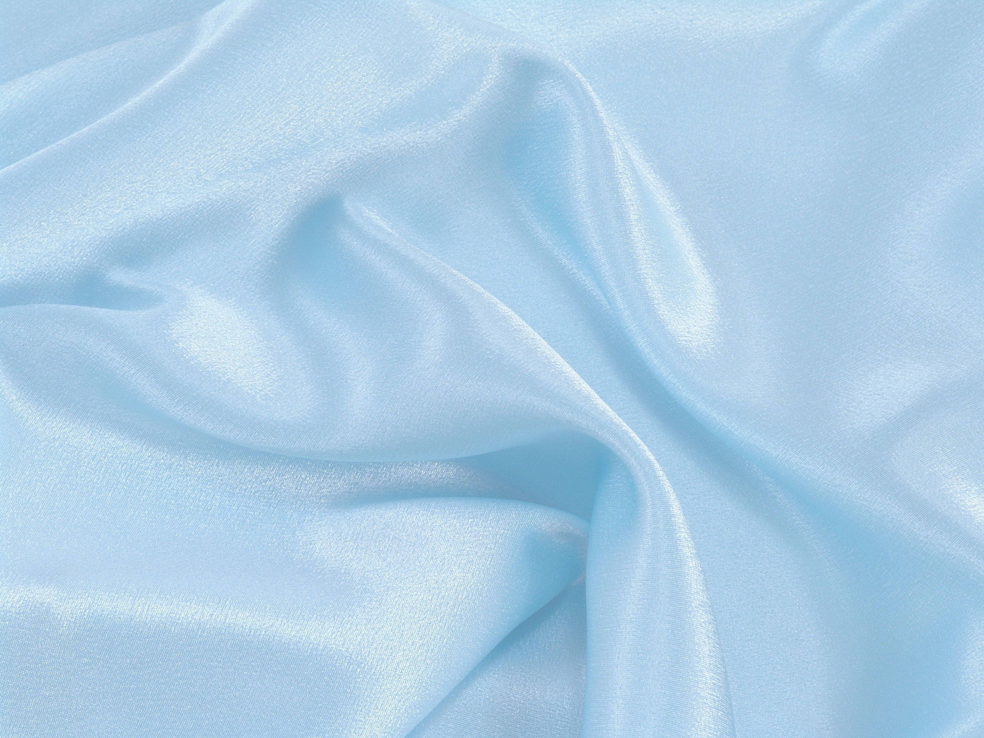 Aesthetic Baby Blue 桌布 壁紙 — 柔軟的淺藍色緞面布料，在均勻光線下呈現柔和皺褶和細微光澤。