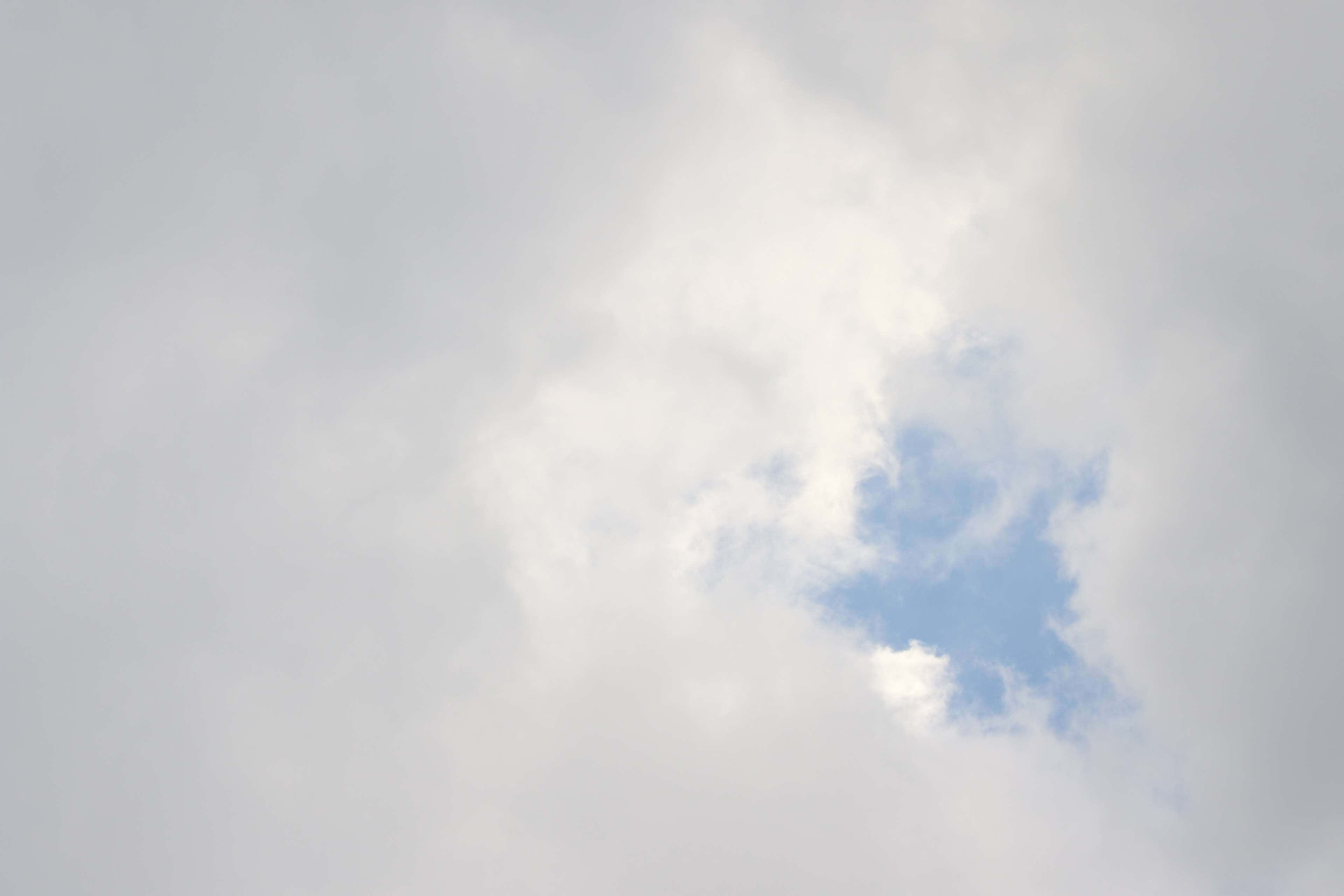 雲朵 桌布 壁紙 — 柔軟的白雲在淡藍色的天空中飄動，露出一小片晴朗的天空。
