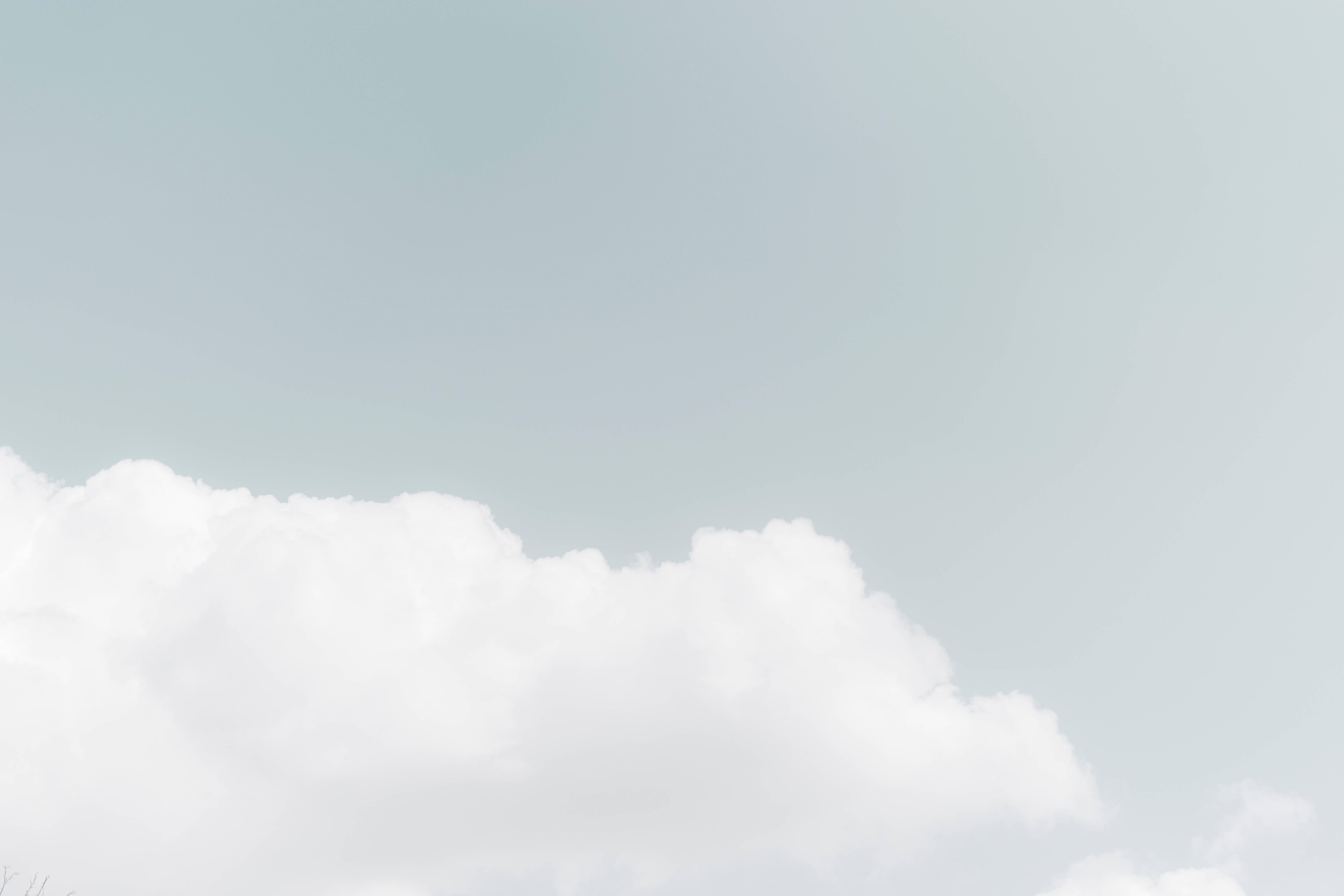 白色 桌布 壁紙 — 柔軟的白雲在淡藍色的天空中飄動，構成寧靜簡約的畫面。