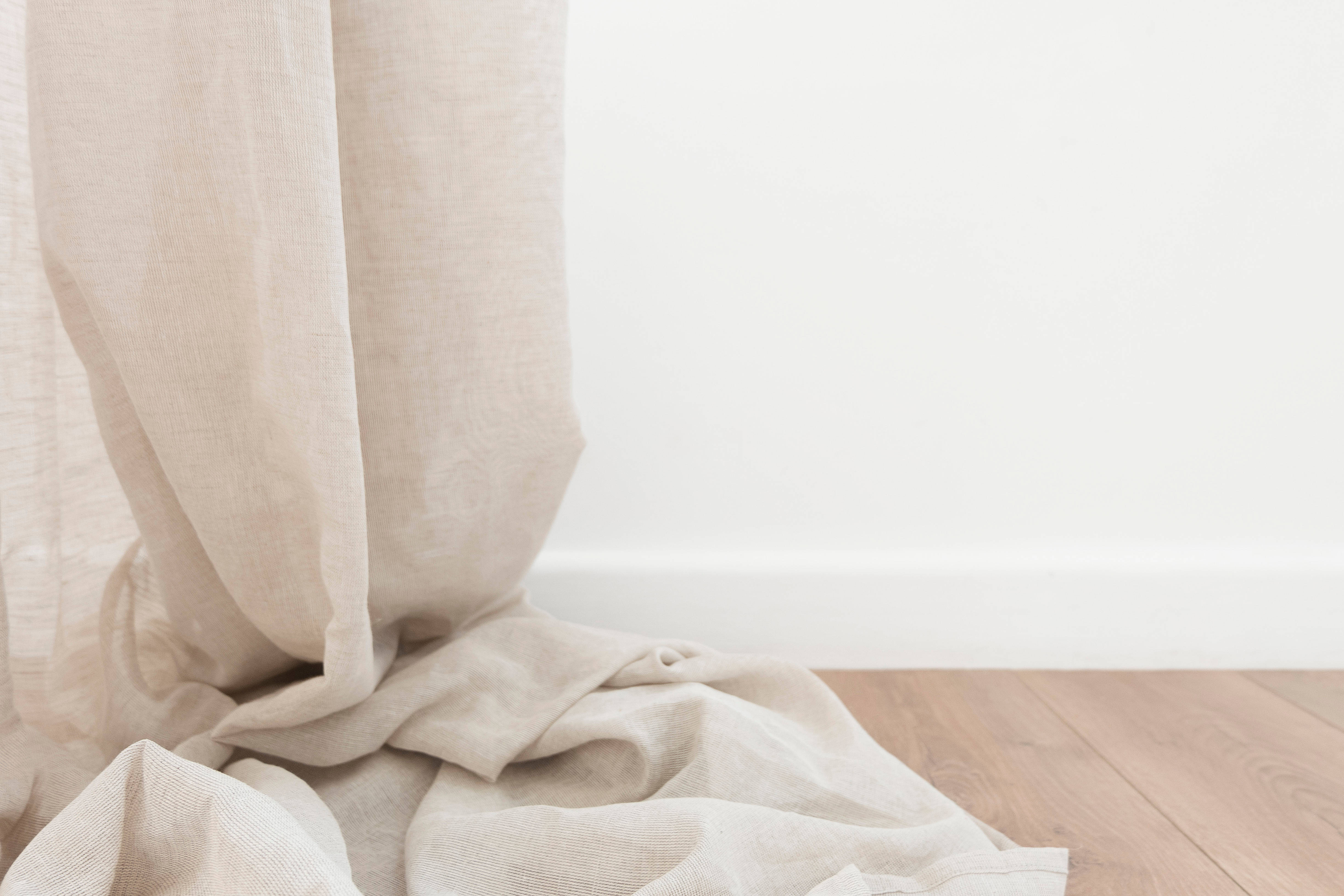 Beige Minimalist 桌布 壁紙 — 柔軟的米色亞麻窗簾優雅地垂落在簡約木地板上，襯著純白牆壁。