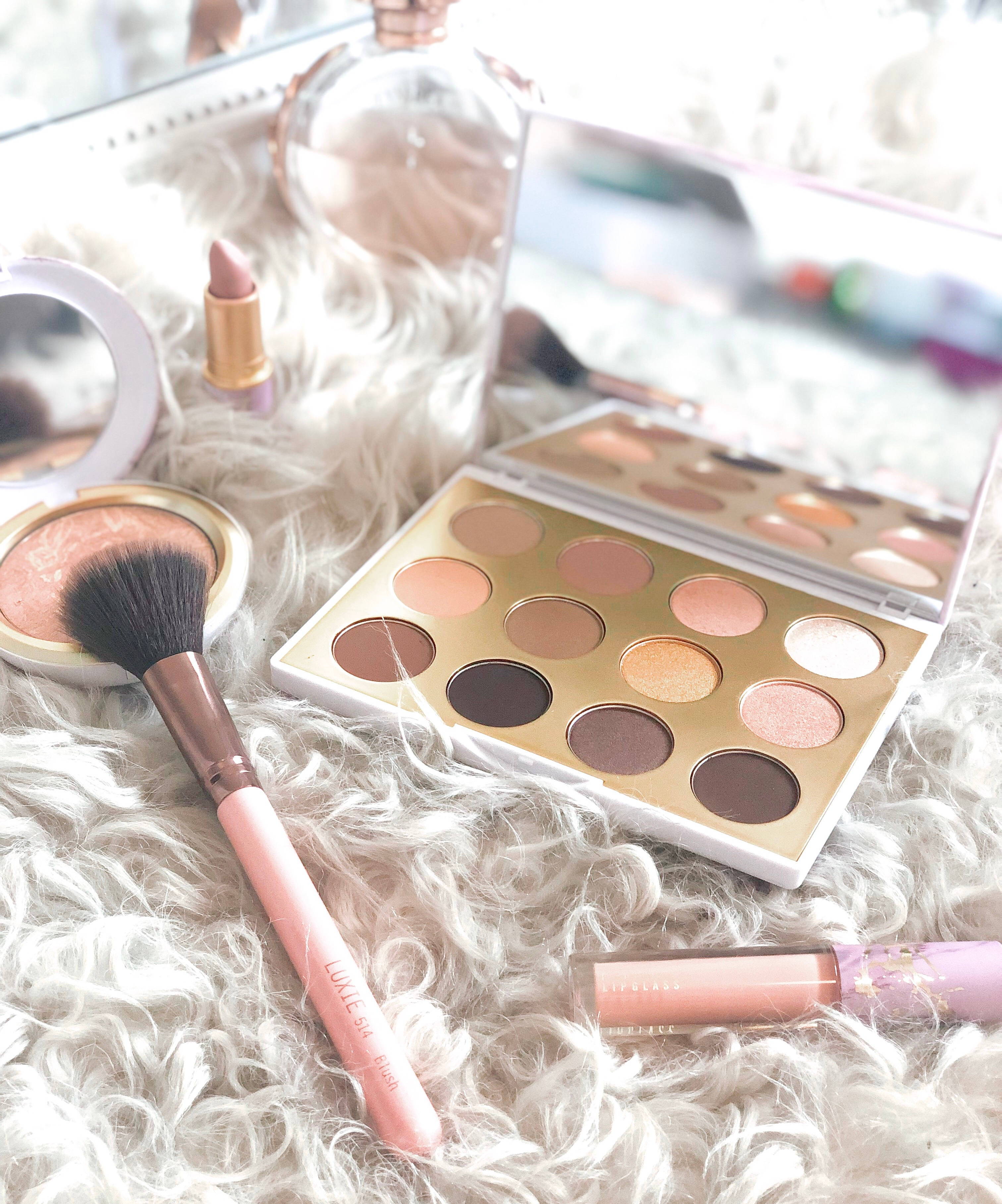 Cosmetics 桌布 壁紙 — 柔軟的粉紅色和金色化妝品系列放在毛絨白色地毯上，鏡面反射出產品。