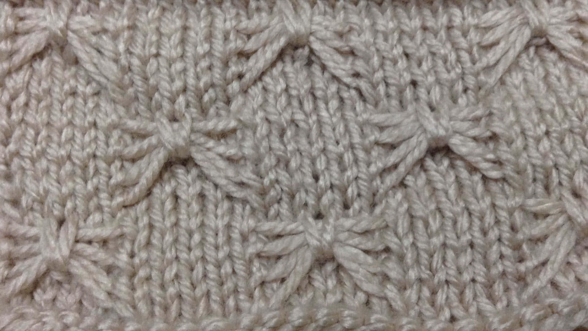 Butterfly Stitch 桌布 壁紙 — 柔軟米色針織布料的特寫，帶有重複的葉狀紋理圖案。