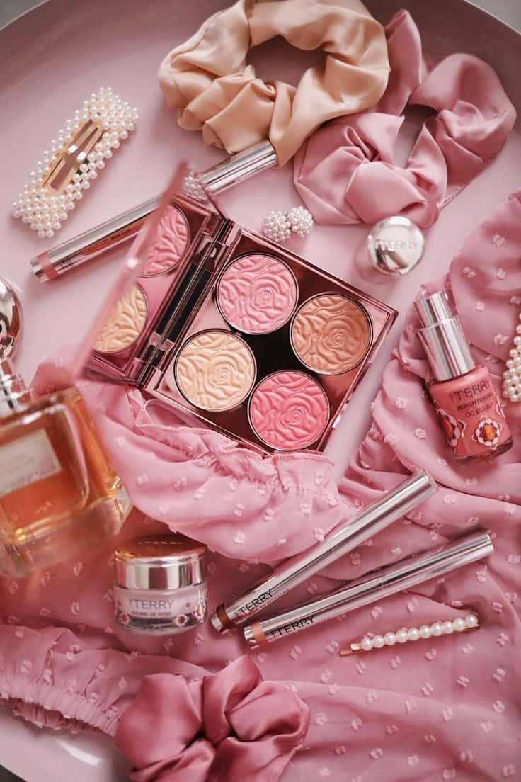 Cosmetic 桌布 壁紙 — 柔軟粉紅色的Terry美容產品平鋪擺放，包括腮紅、唇彩和配件，排列在帶有紋理的粉紅色布料上。