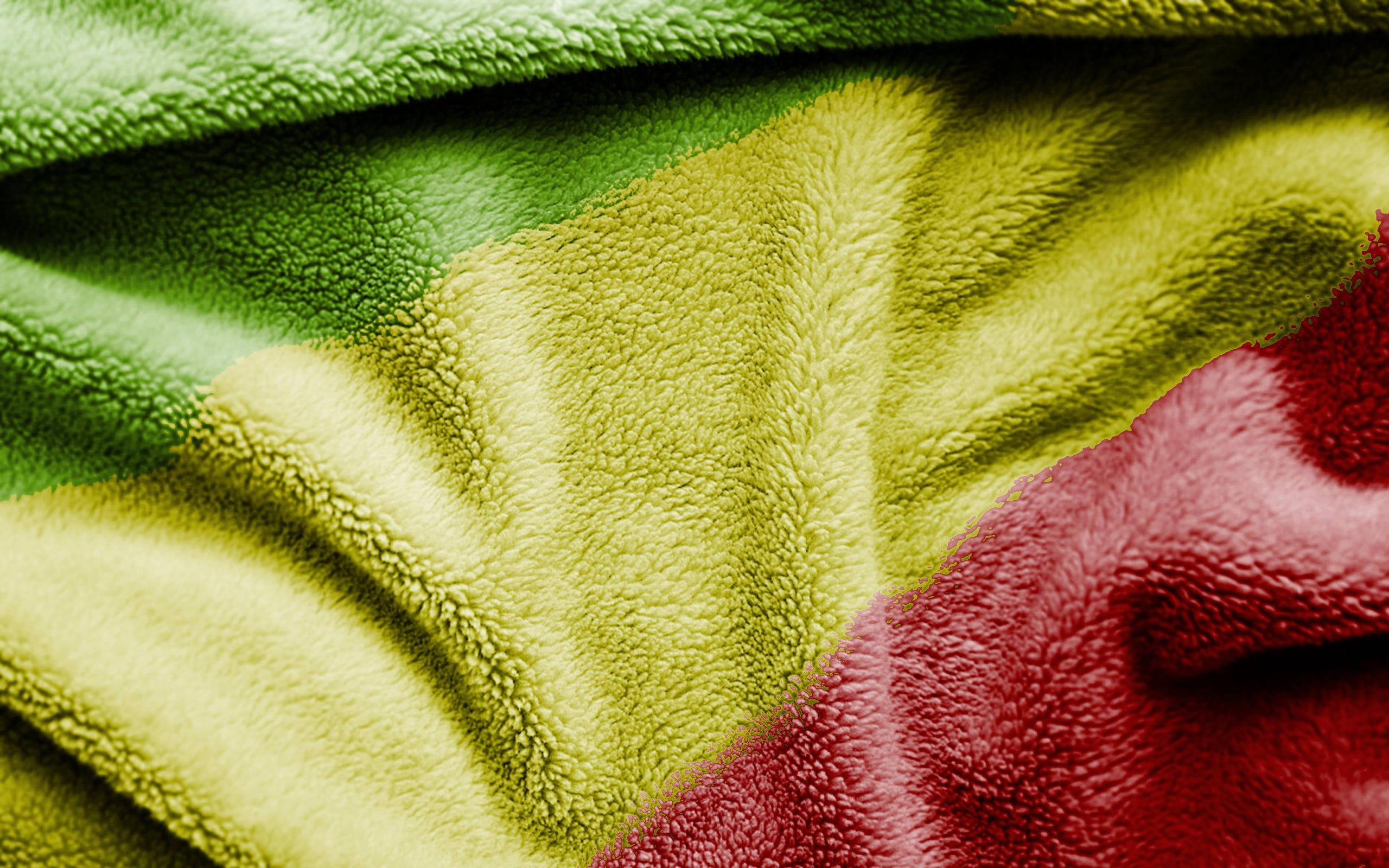 Senegal 桌布 壁紙 — 柔軟質感毛毯的特寫，帶有鮮豔的綠色、黃色和紅色部分，以柔和的褶皺垂墜。